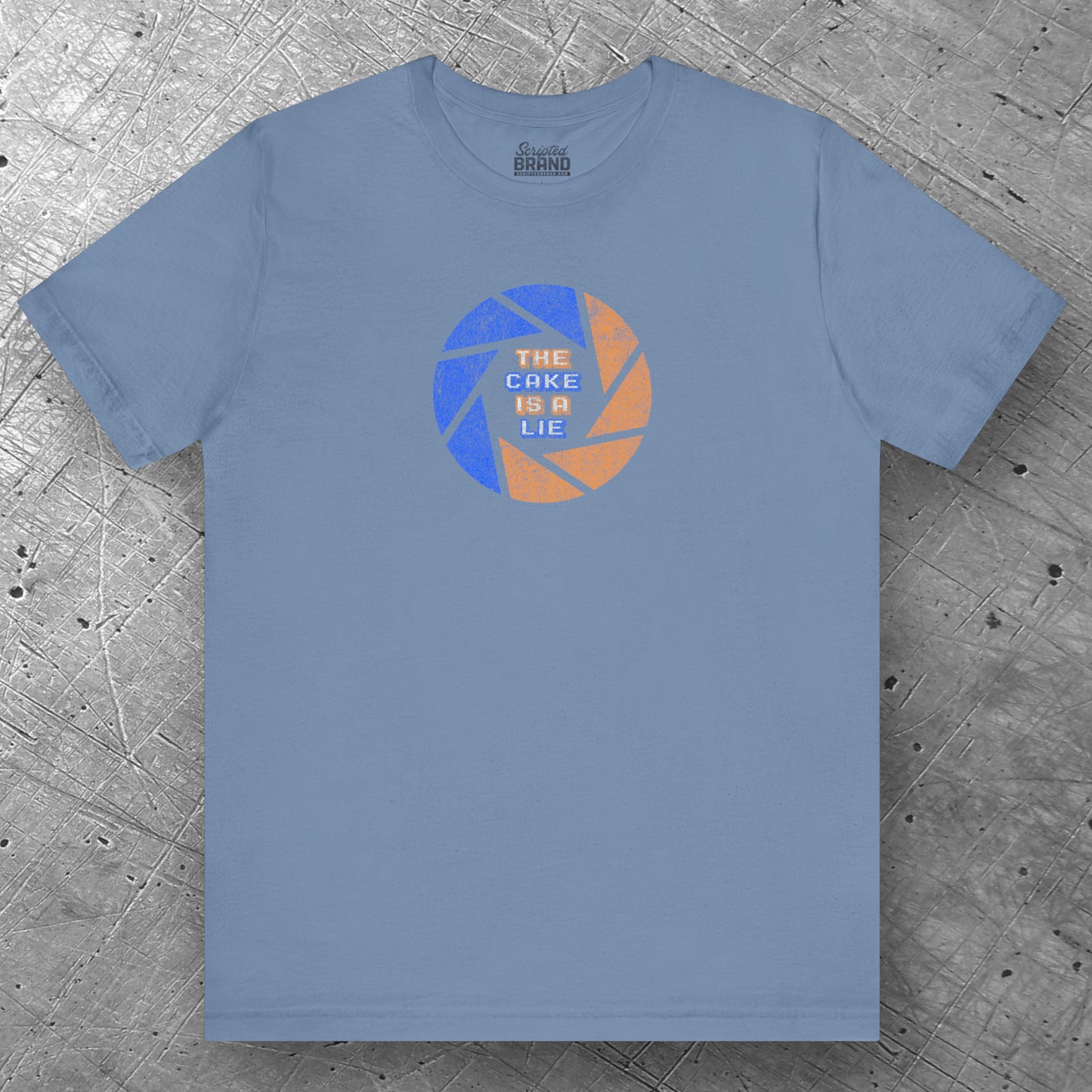 Front view of a steel blue colored soft Bella+Canvas 3001 short-sleeve t-shirt featuring the phrase The Cake Is a Lie, along with the Aperture Laboratories shutter logo from the video game Portal and Portal 2 in a vintage distressed style, sold by ScriptedBrand.