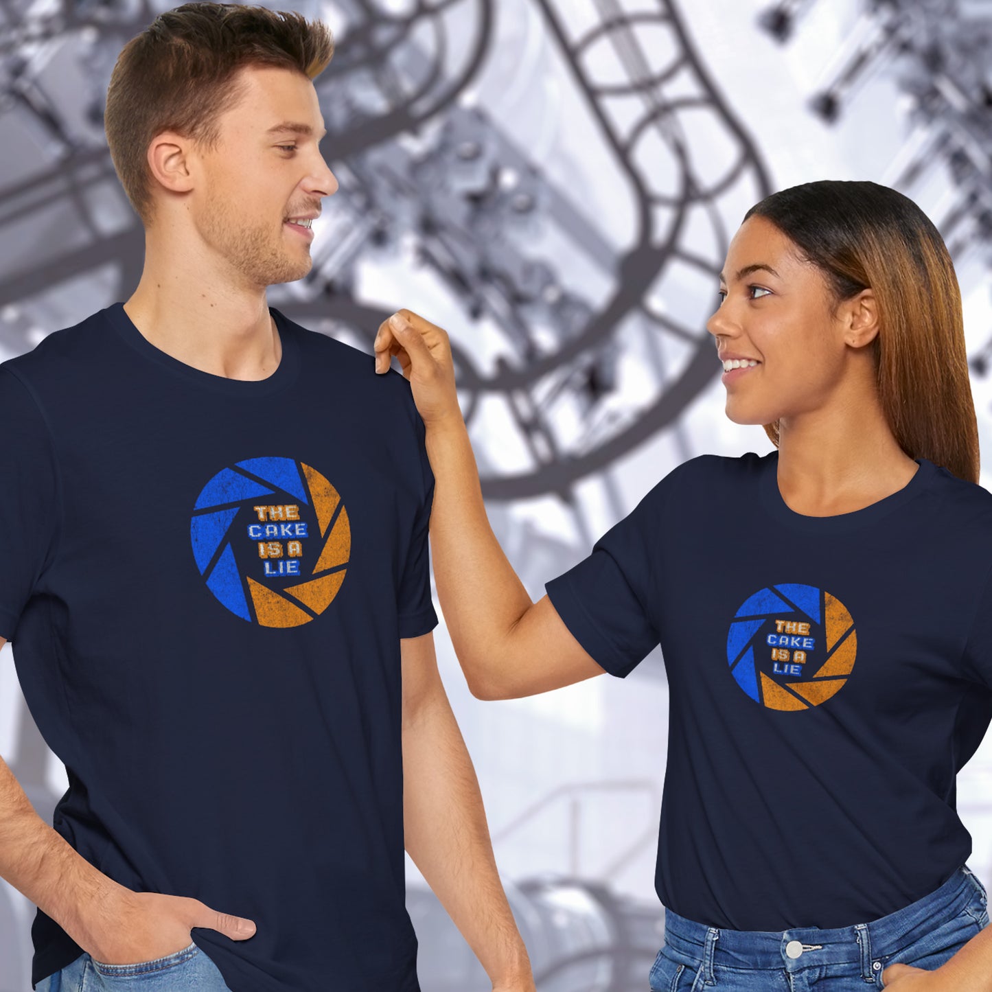 2 models wearing navy blue soft Bella+Canvas 3001 short-sleeve t-shirts featuring the phrase The Cake Is a Lie, along with the Aperture Laboratories shutter logo from the video game Portal and Portal 2 in a vintage distressed style, sold by ScriptedBrand.