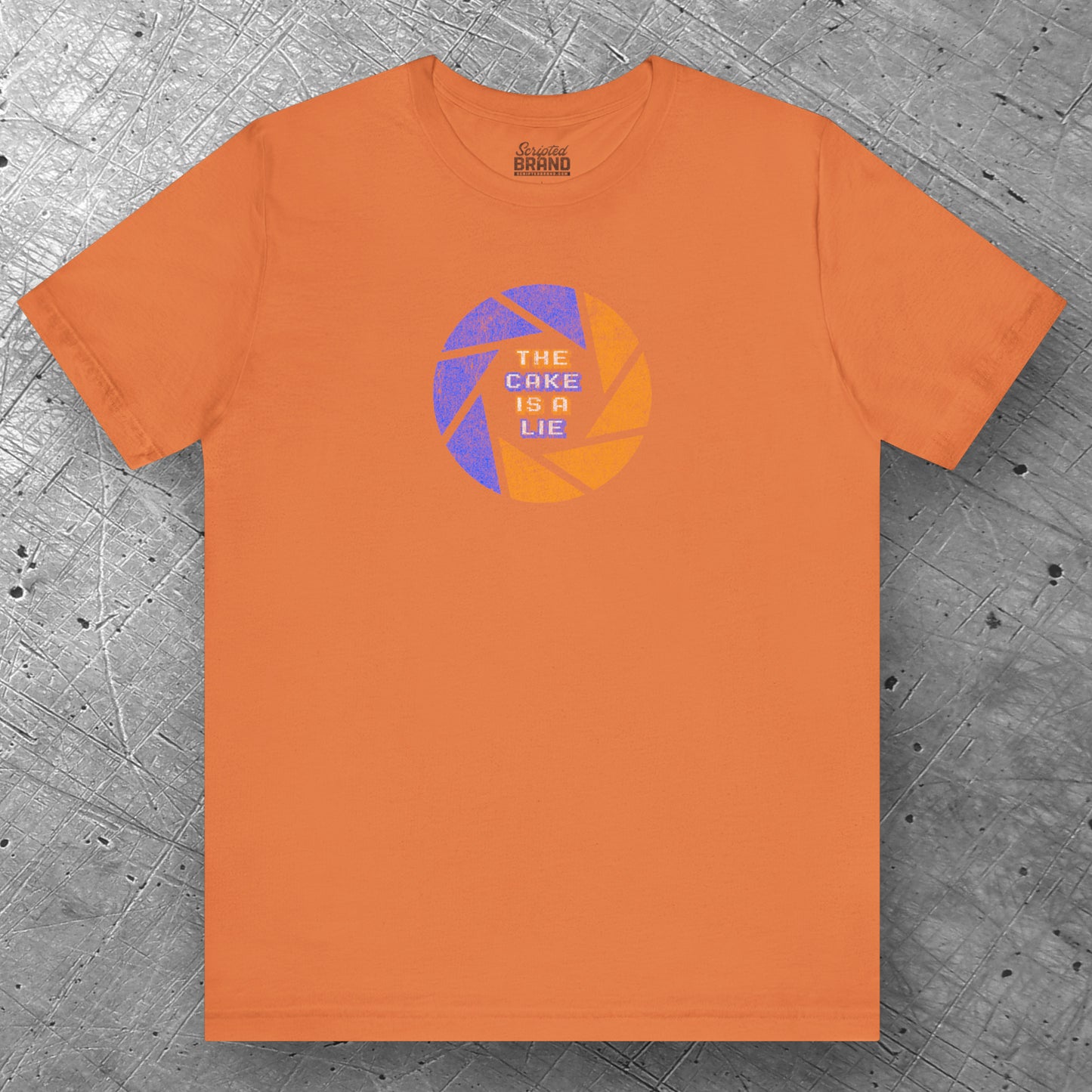 Front view of a burnt orange colored soft Bella+Canvas 3001 short-sleeve t-shirt featuring the phrase The Cake Is a Lie, along with the Aperture Laboratories shutter logo from the video game Portal and Portal 2 in a vintage distressed style, sold by ScriptedBrand.