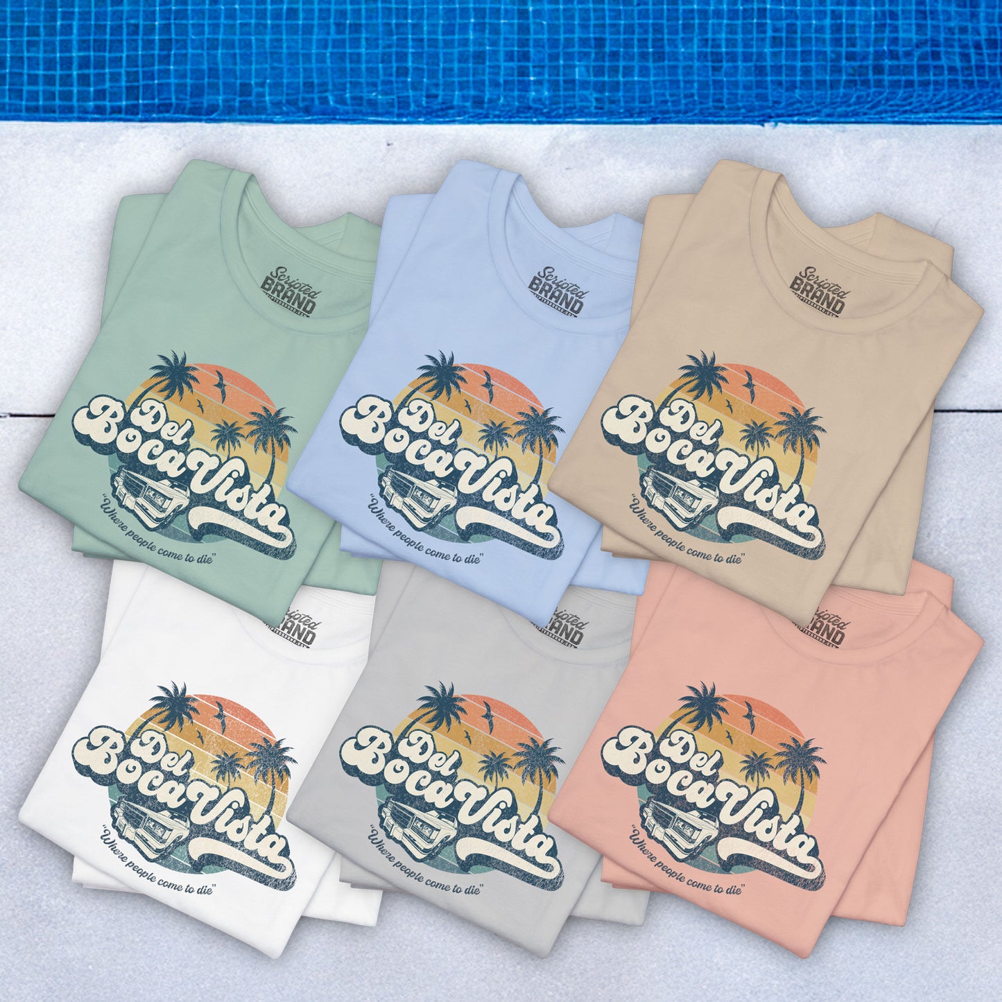 Group of 6 folded Soft Bella+Canvas 3001 short-sleeve t-shirts featuring a Del Boca Vista logo graphic (uniquely designed by ScriptedBrand), including the phrase Where People Come To Die, inspired by the TV show Seinfeld, in a vintage distressed style, laid out near a pool.