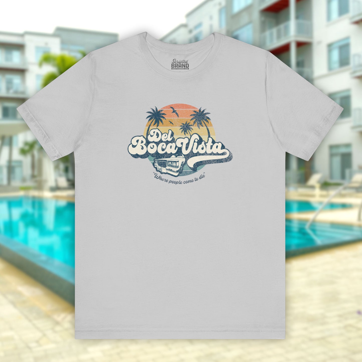 Front view of a solid athletic grey Soft Bella+Canvas 3001 short-sleeve t-shirt featuring a Del Boca Vista logo graphic (uniquely designed by ScriptedBrand), including the phrase Where People Come To Die, inspired by the TV show Seinfeld, in a vintage distressed style.