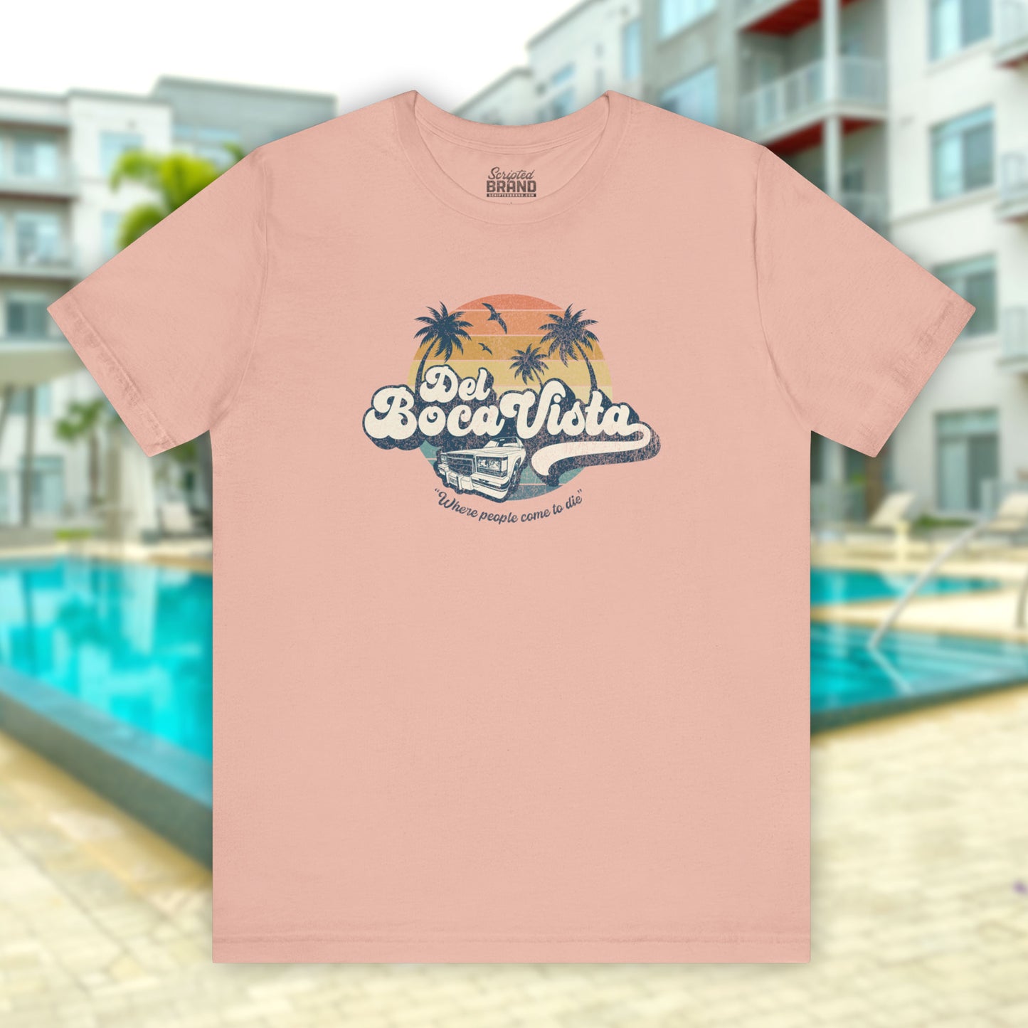 Front view of a peach Soft Bella+Canvas 3001 short-sleeve t-shirt featuring a Del Boca Vista logo graphic (uniquely designed by ScriptedBrand), including the phrase Where People Come To Die, inspired by the TV show Seinfeld, in a vintage distressed style.