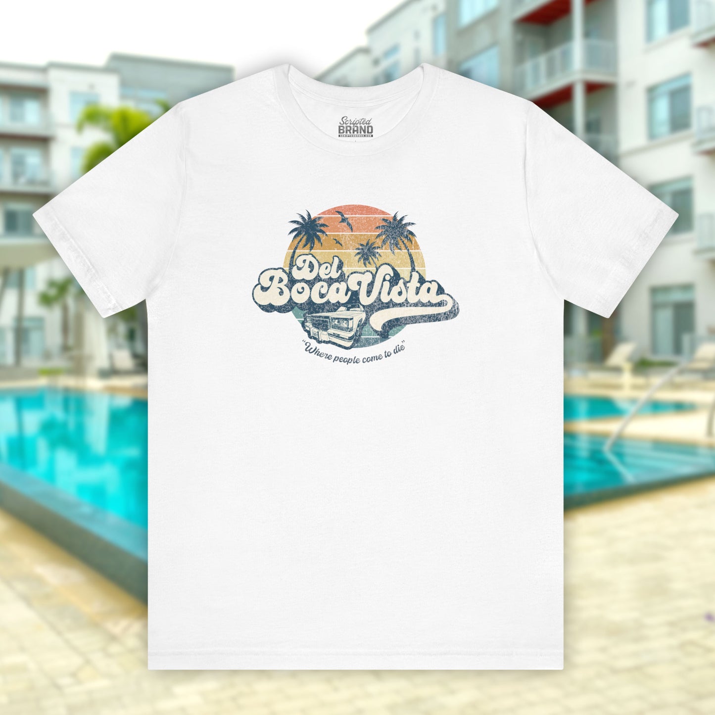 Front view of a white Soft Bella+Canvas 3001 short-sleeve t-shirt featuring a Del Boca Vista logo graphic (uniquely designed by ScriptedBrand), including the phrase Where People Come To Die, inspired by the TV show Seinfeld, in a vintage distressed style.