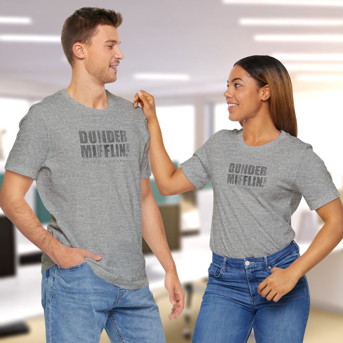 Two people wearing gray t-shirts featuring the Dunder Mifflin logo from the TV show The Office in a vintage distressed style.