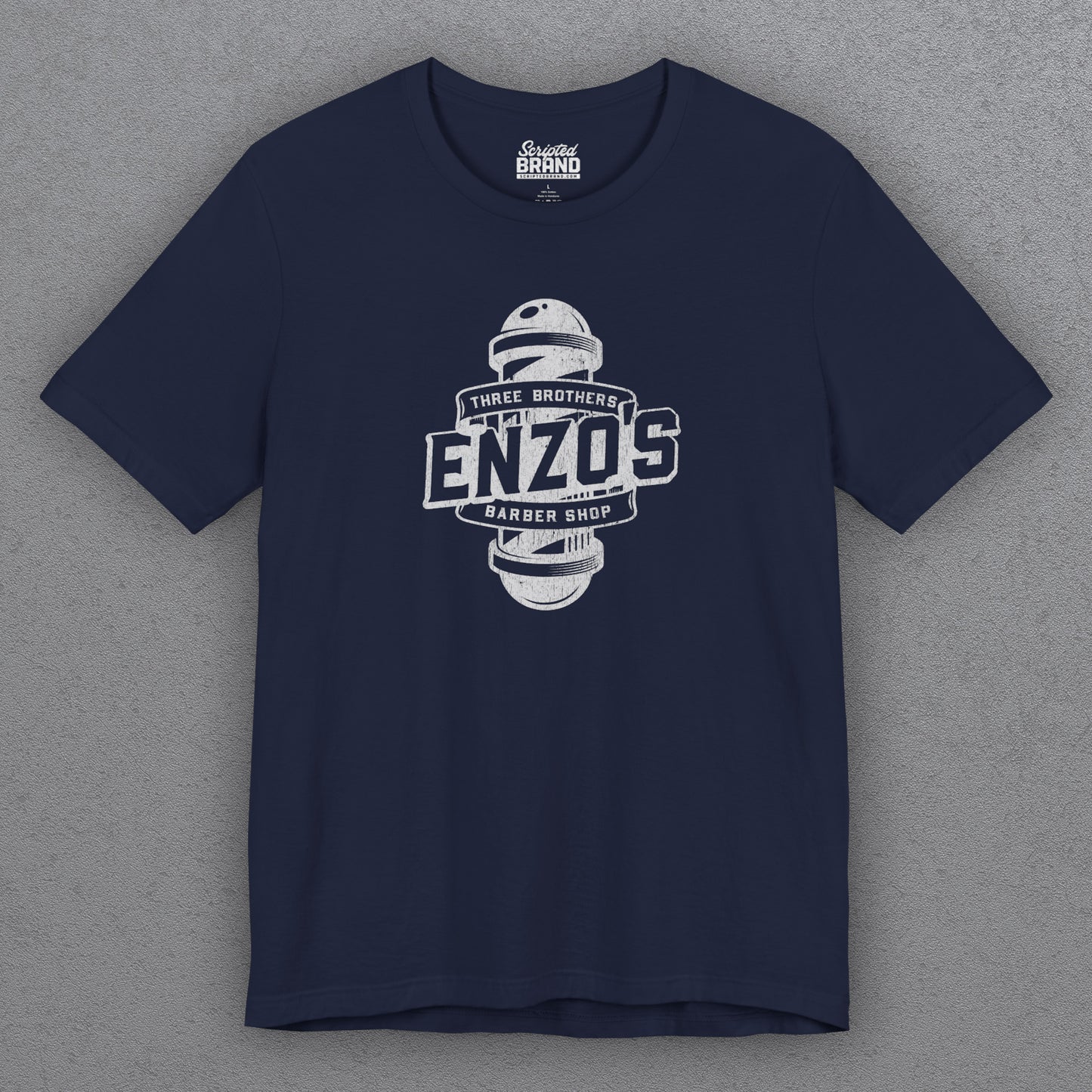 Front view of a navy blue t-shirt with the Enzo's Barber Shop logo graphic inspired by the TV show Seinfeld in a vintage distressed style.