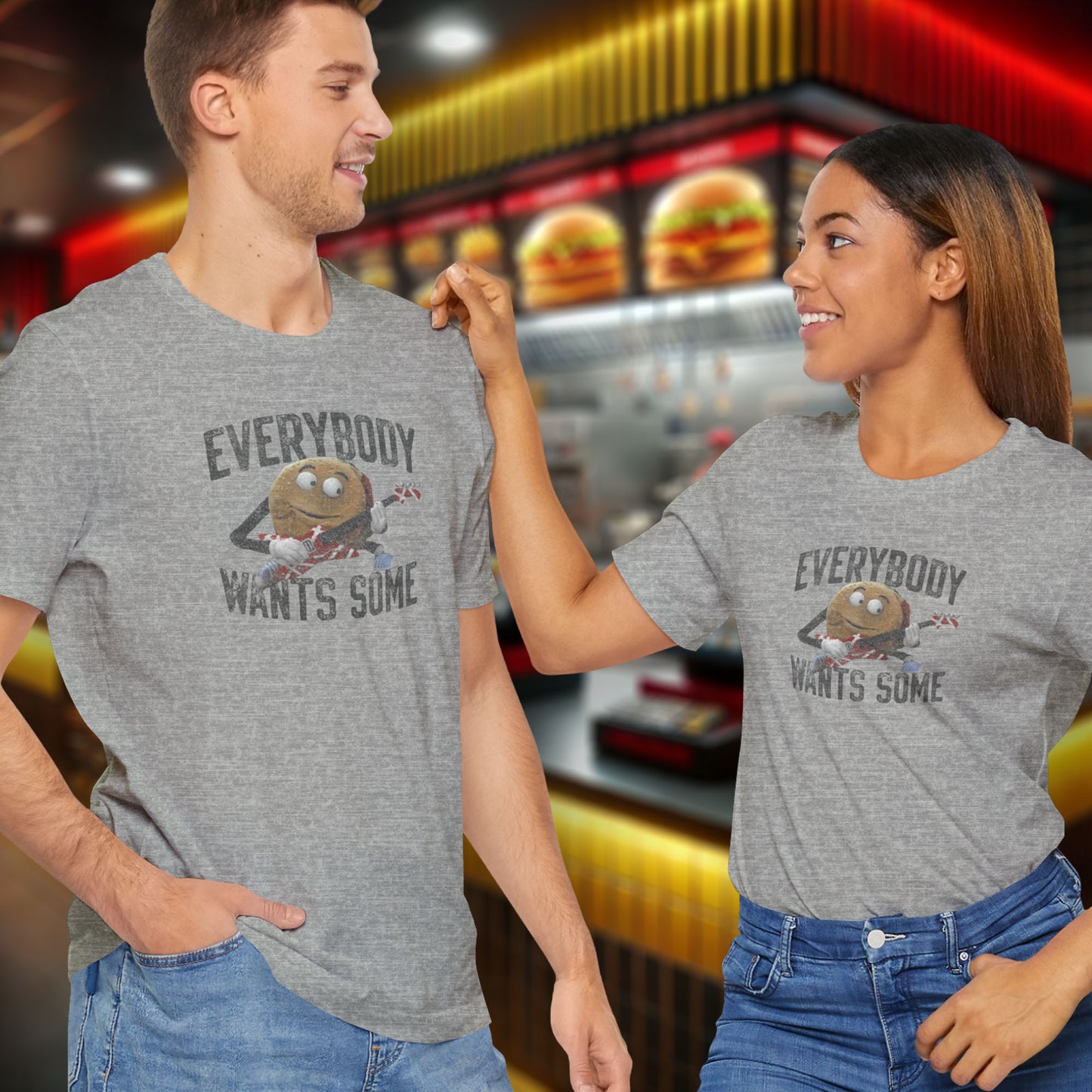 Man and woman wearing gray t-shirts with the phrase EVERYBODY WANTS SOME and a graphic of the guitar playing hamburger from the movie Better Off Dead in a vintage style.