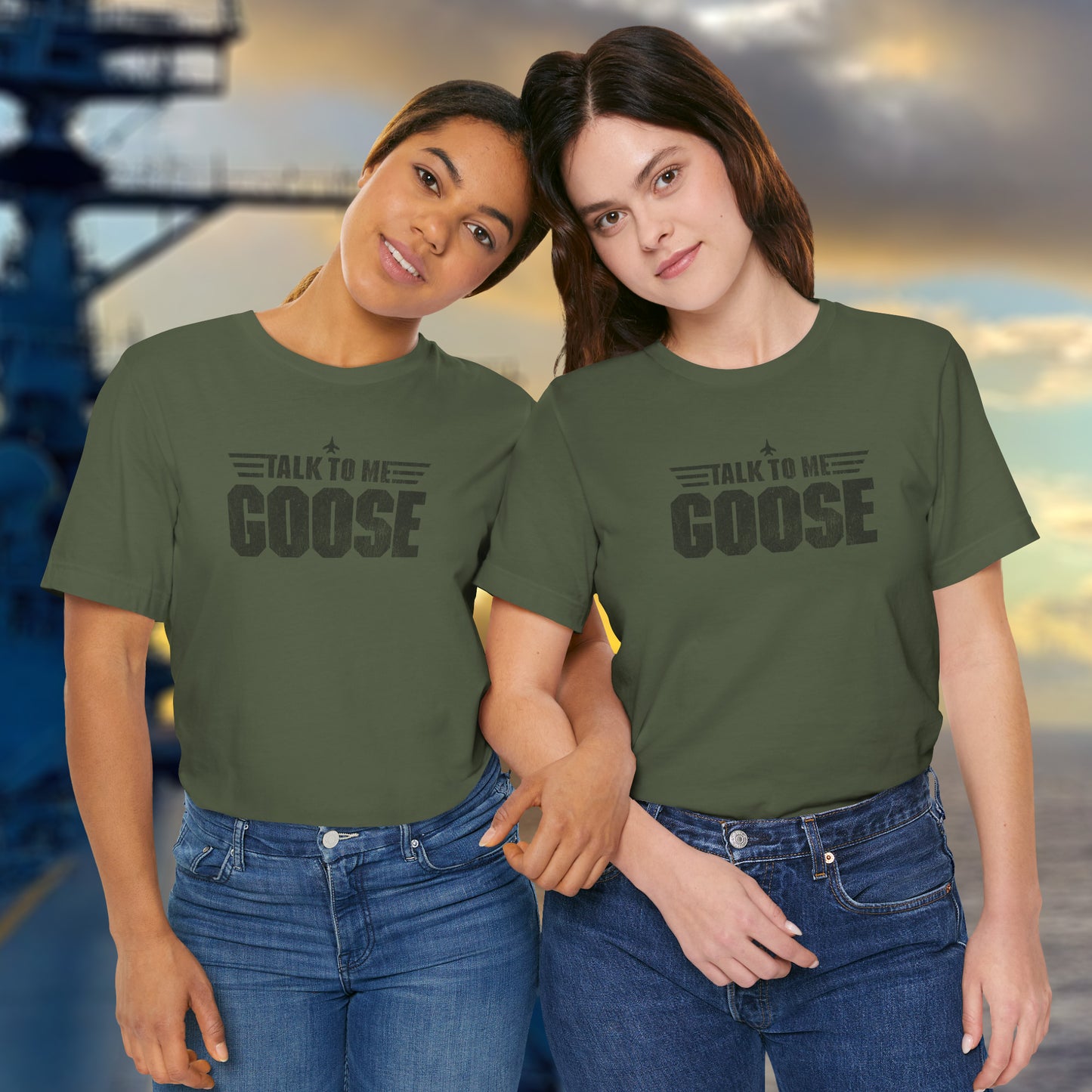 2 female models wearing military green soft unisex Bella+Canvas 3001 short-sleeve t-shirts featuring a graphic designed by ScriptedBrand in a vintage distressed style with the text TALK TO ME GOOSE, inspired by the Movie Top Gun.