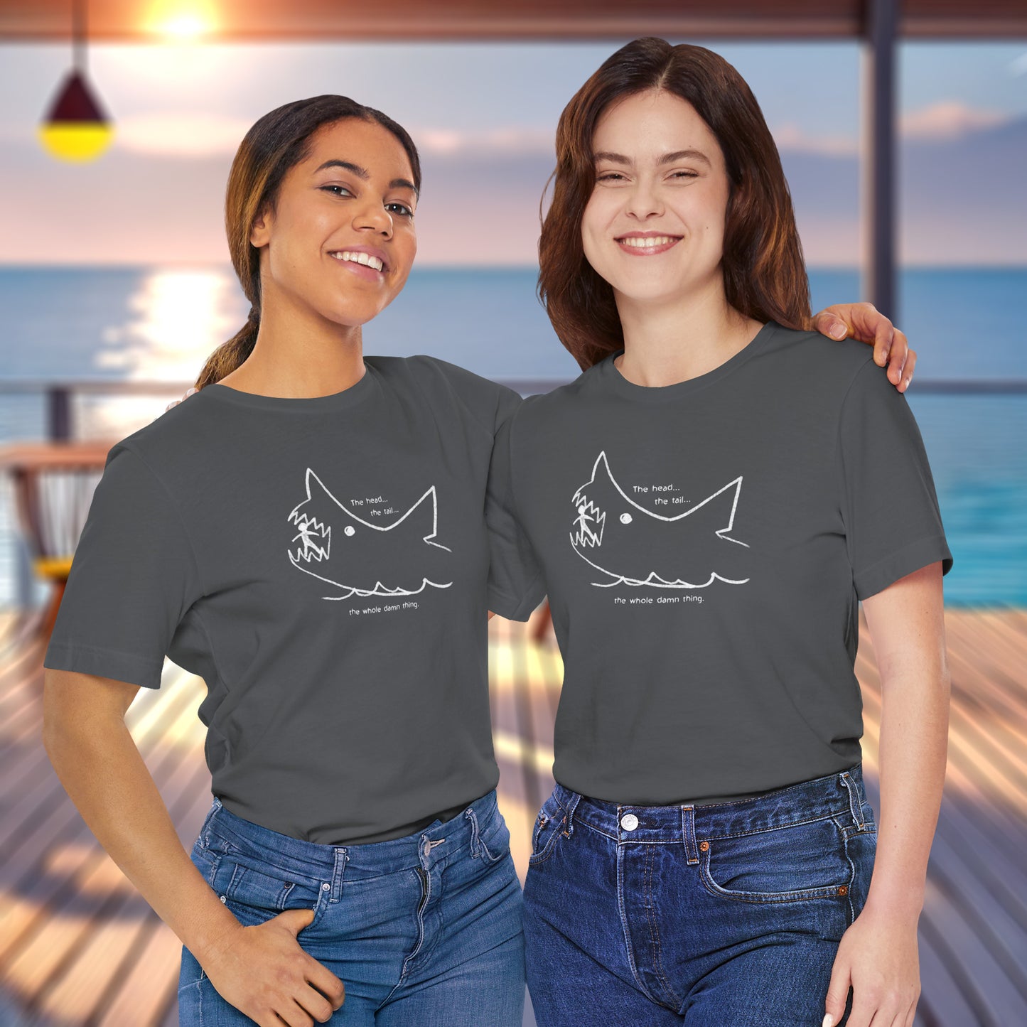 2 Female models wearing a asphalt gray colored soft short-sleeve Bella+Canvas 3001 t-shirt featuring the chalkboard drawing of a shark eating a person, drawn by Quint in the movie Jaws.