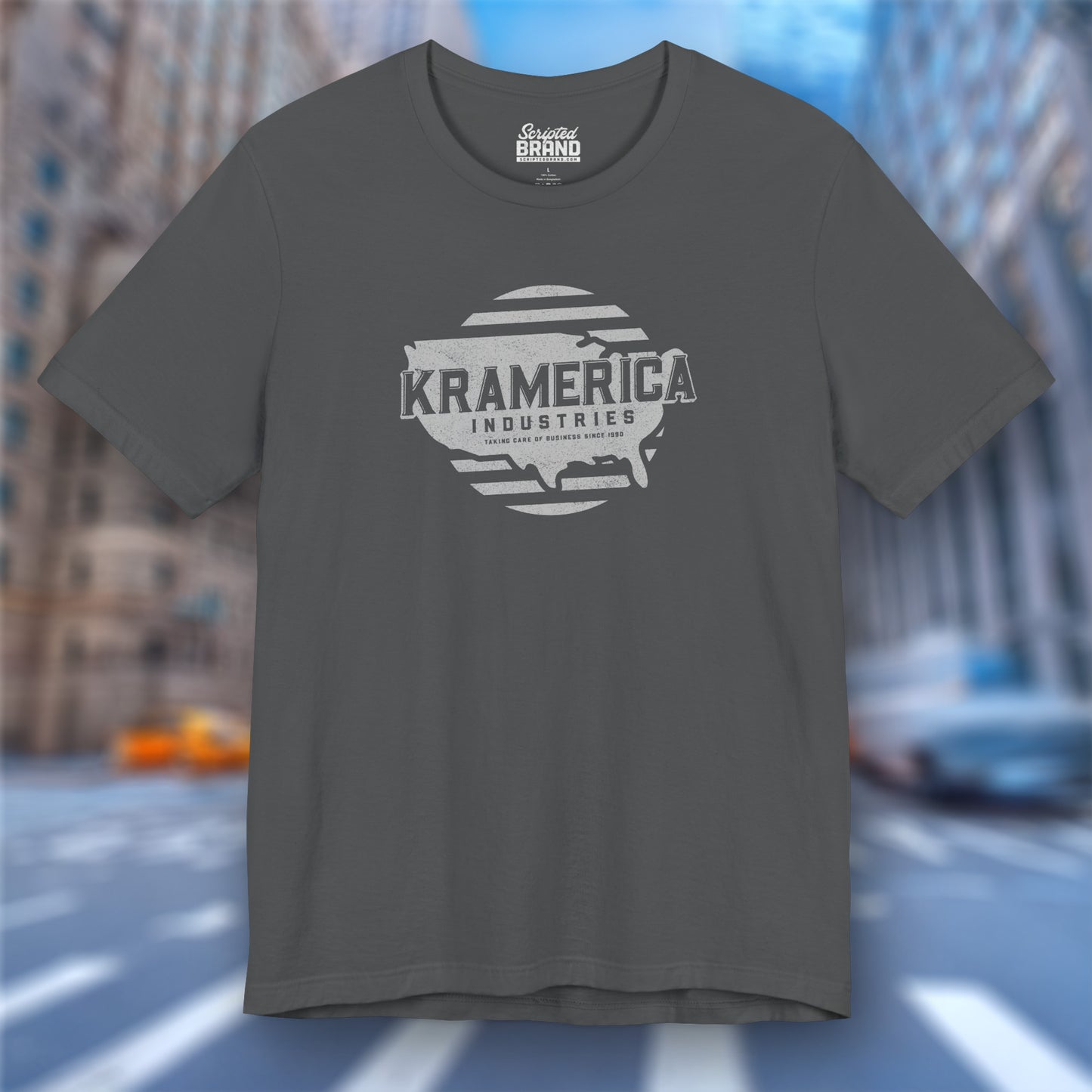 Front view of an asphalt grey soft unisex Bella+Canvas 3001 short-sleeve t-shirt featuring a unique Kramerica Industries logo graphic, designed by ScriptedBrand in a vintage distressed style, and inspired by the TV show Seinfeld.