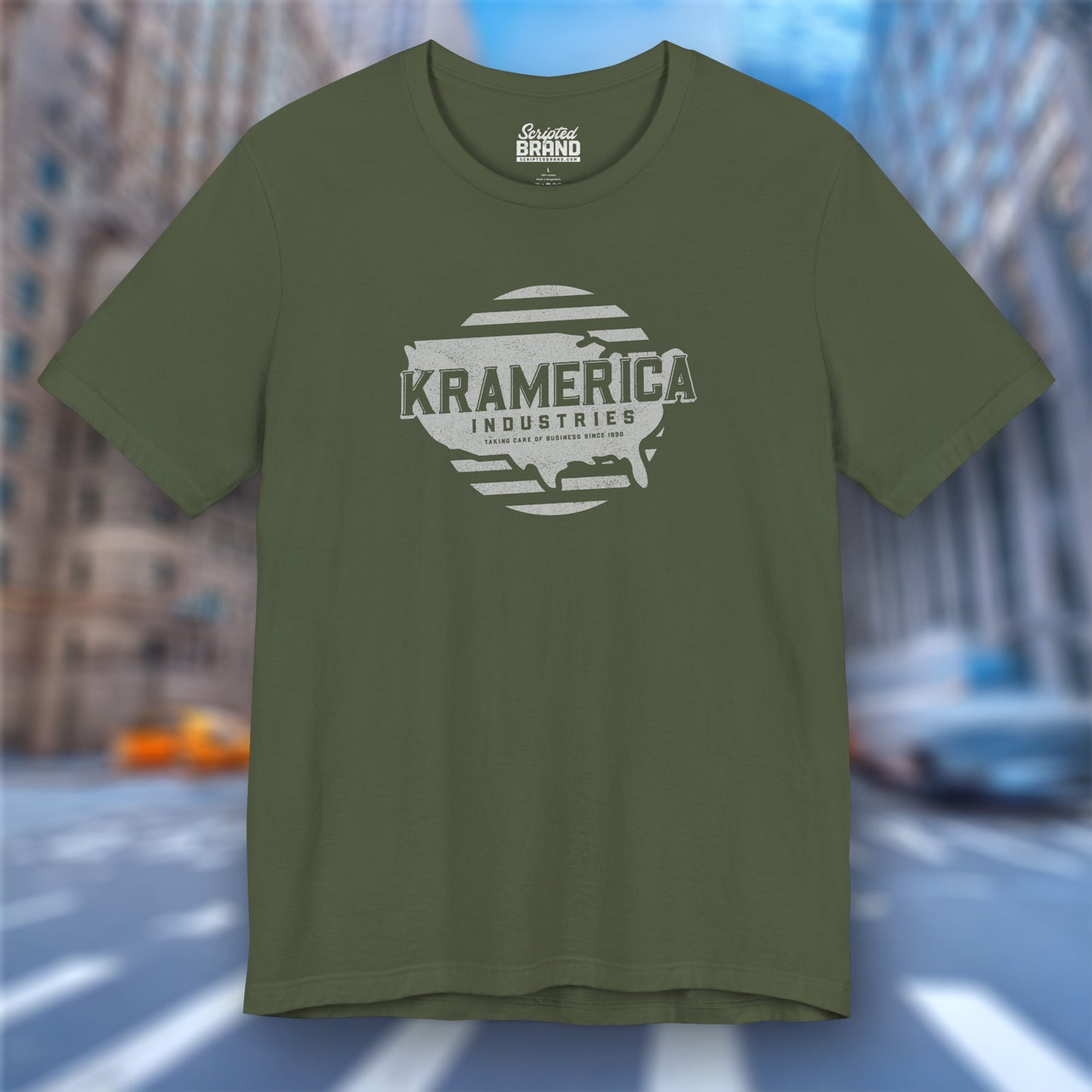 Front view of a military green soft unisex Bella+Canvas 3001 short-sleeve t-shirt featuring a unique Kramerica Industries logo graphic, designed by ScriptedBrand in a vintage distressed style, and inspired by the TV show Seinfeld.