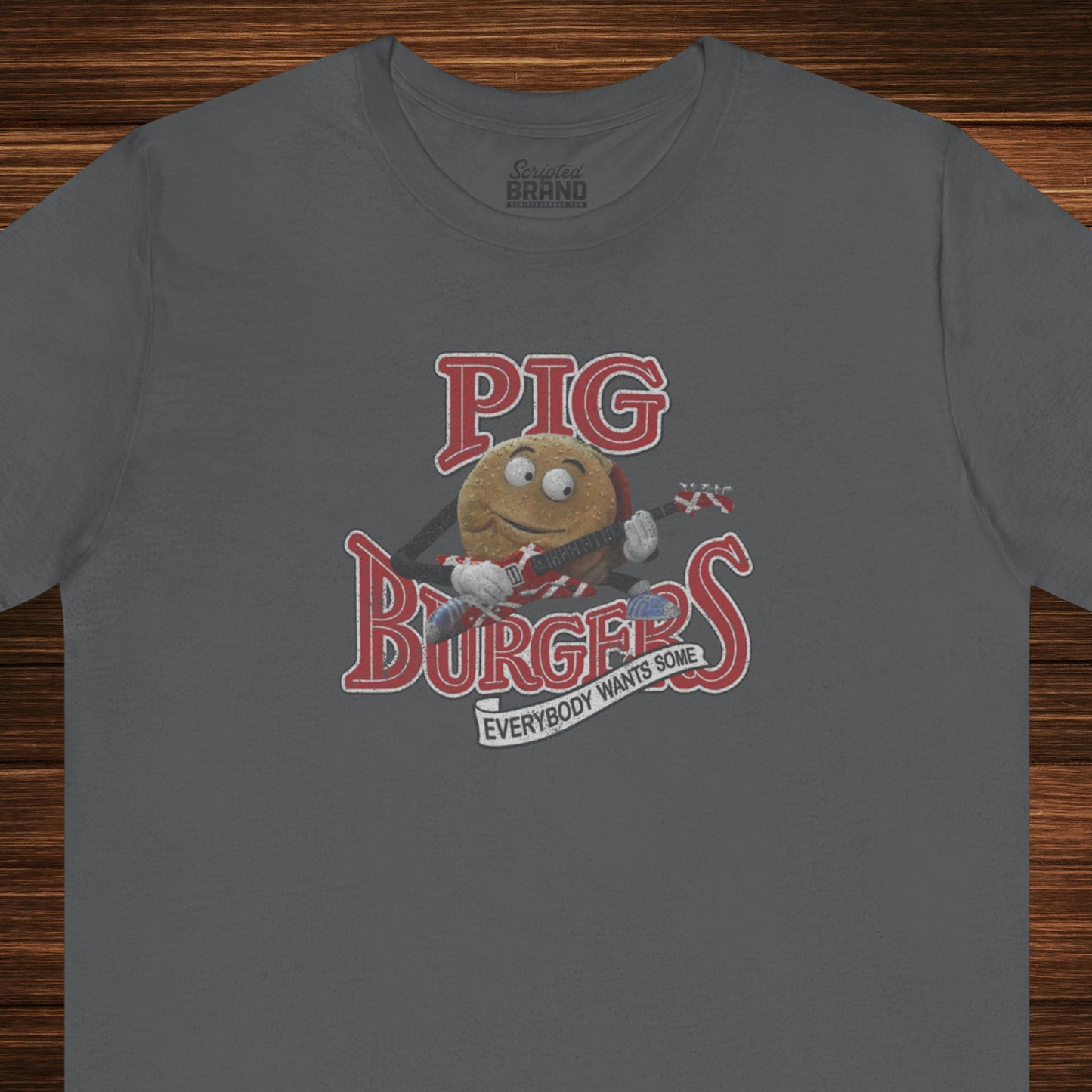 Front view of an asphalt grey colored soft Bella+Canvas 3001 short-sleeve t-shirt featuring a graphic of the fictional Pig Burgers logo from the movie Better Off Dead, along with the Van Halen singing hamburger playing guitar, with the small subhead phrase EVERYBODY WANTS SOME. The graphic is designed in a vintage distressed style, sold by ScriptedBrand.