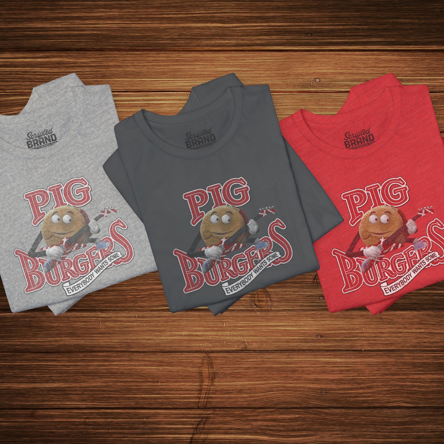 Group of 3 folded soft Bella+Canvas 3001 short-sleeve t-shirts featuring a graphic of the fictional Pig Burgers logo from the movie Better Off Dead, along with the Van Halen singing hamburger playing guitar, with the small subhead phrase EVERYBODY WANTS SOME. The graphic is designed in a vintage distressed style, sold by ScriptedBrand.