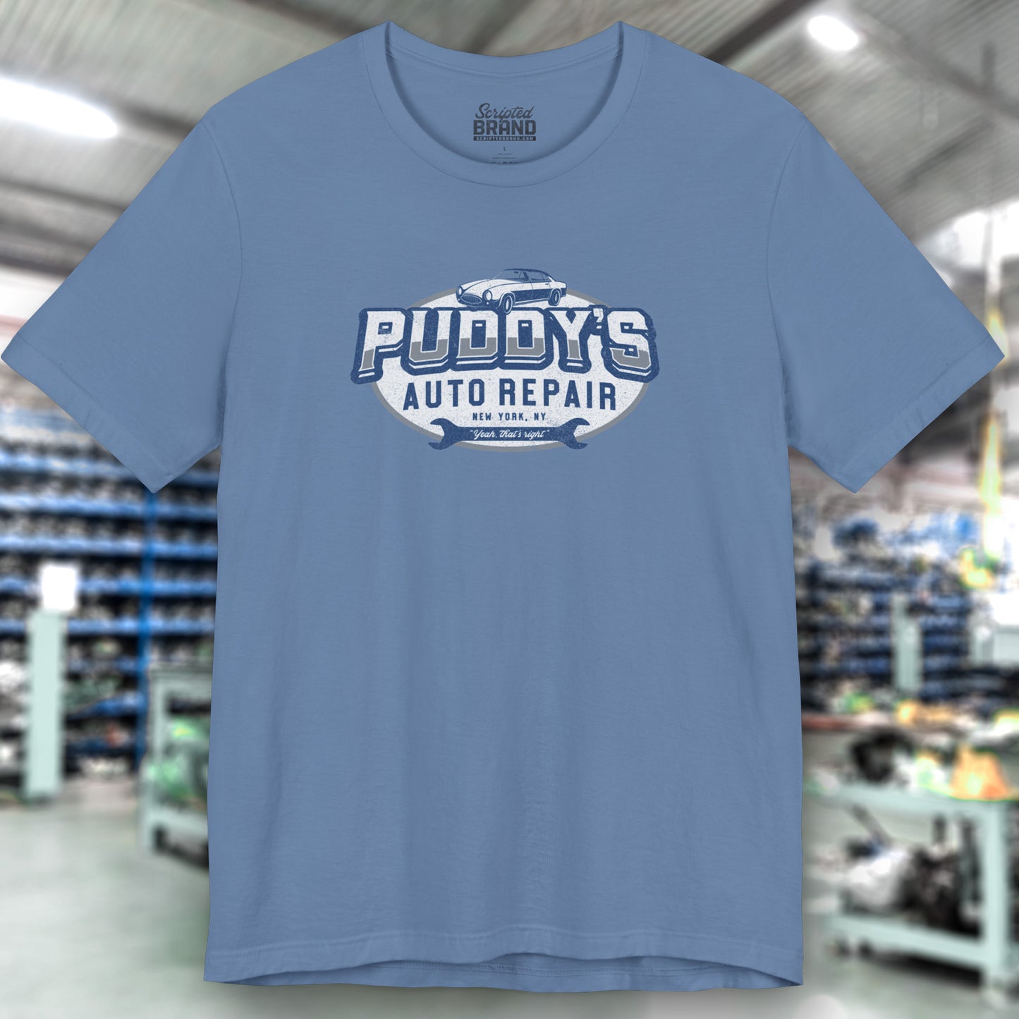 Front view of lavender blue soft short-sleeve t-shirt featuring a Puddy's Auto Repair graphic designed by ScriptedBrand inspired by the TV show Seinfeld in a vintage distressed ink-stamped worn-in style.