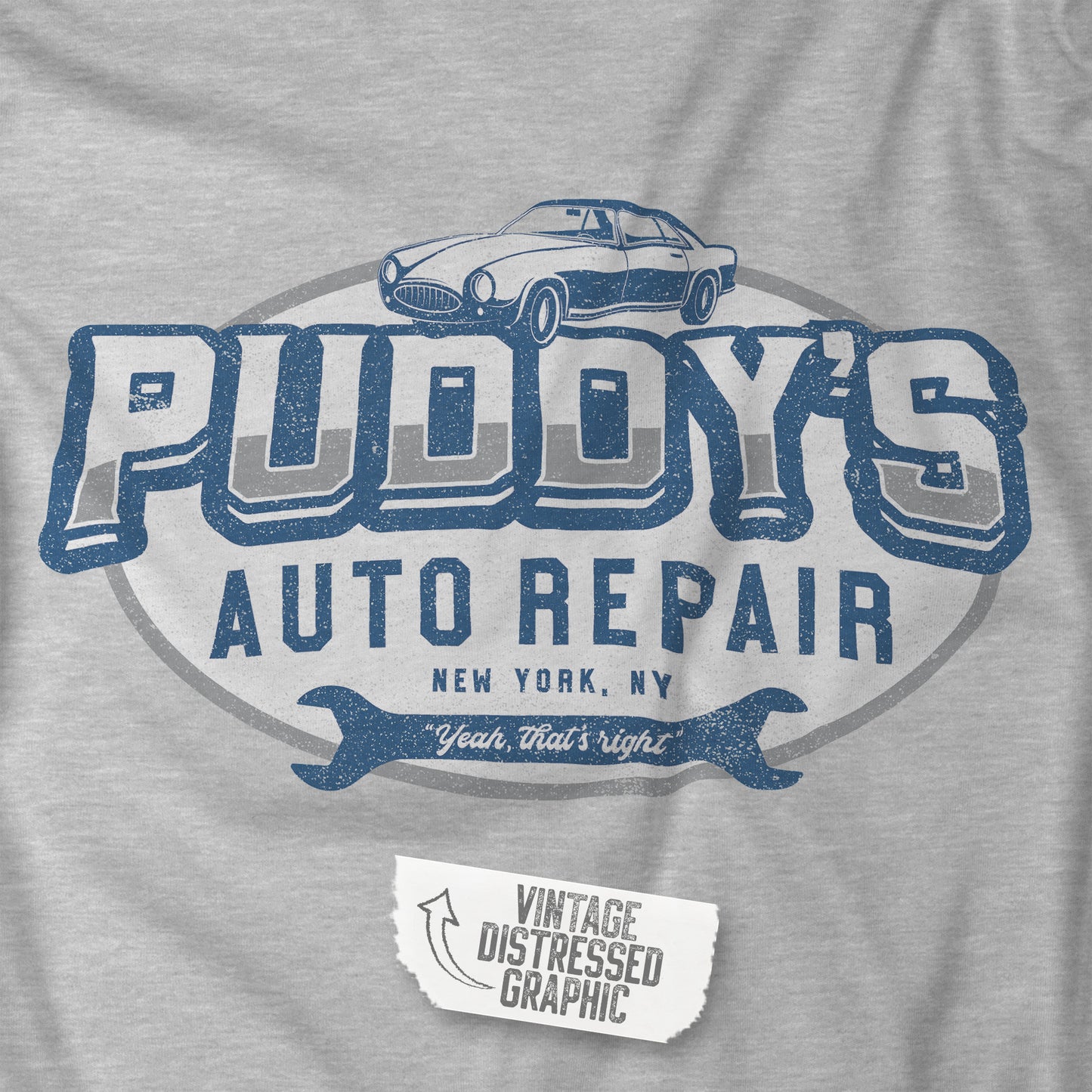 Closeup of an athletic heather grey soft short-sleeve t-shirt featuring a Puddy's Auto Repair logo graphic inspired by the TV show Seinfeld, designed by ScriptedBrand in a vintage distressed style.