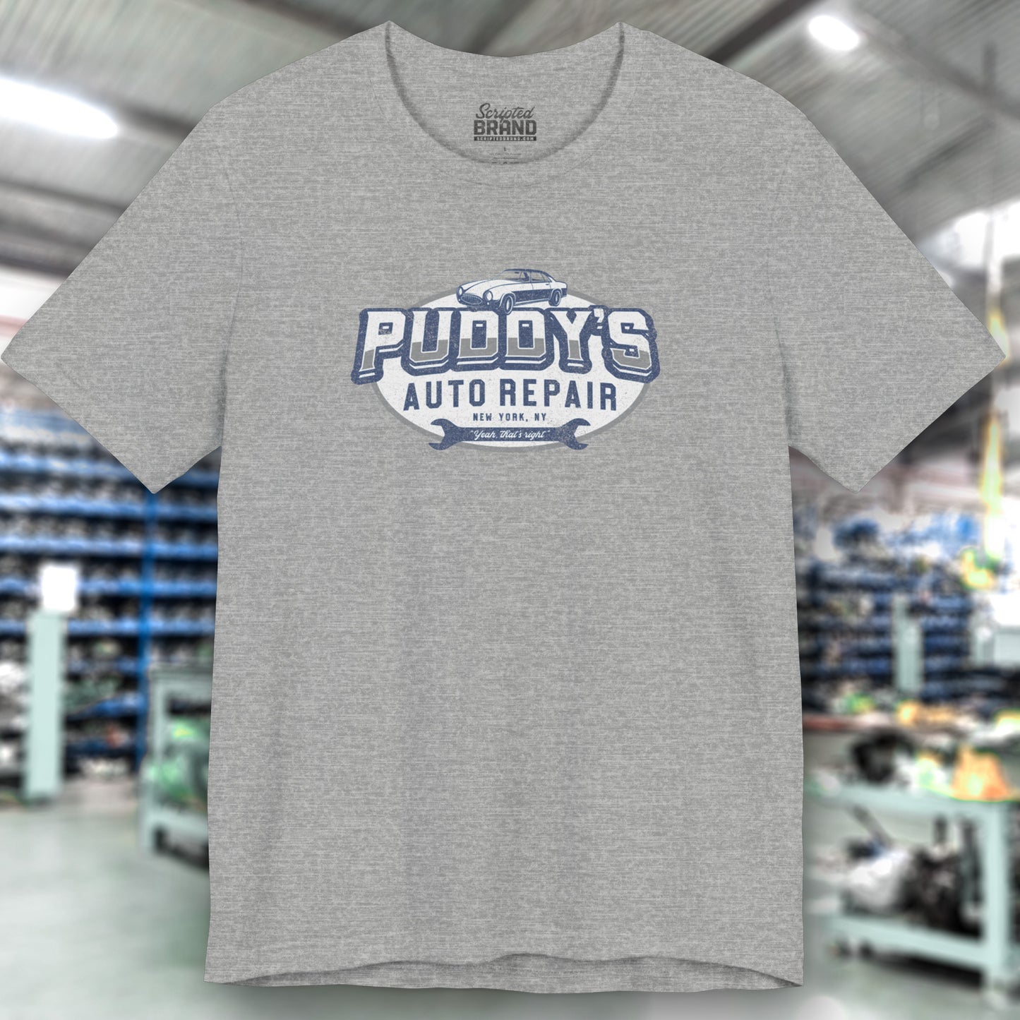 Front view of athletic heather gray soft short-sleeve t-shirt featuring a Puddy's Auto Repair graphic designed by ScriptedBrand inspired by the TV show Seinfeld in a vintage distressed ink-stamped worn-in style.