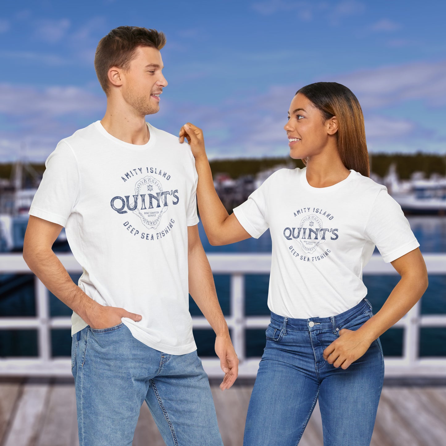2 models wearing soft short-sleeve t-shirts featuring the Quint's Deep Sea Fishing Boat Charters logo graphic inspired by the movie Jaws in a vintage distressed ink-stamped worn-in style.