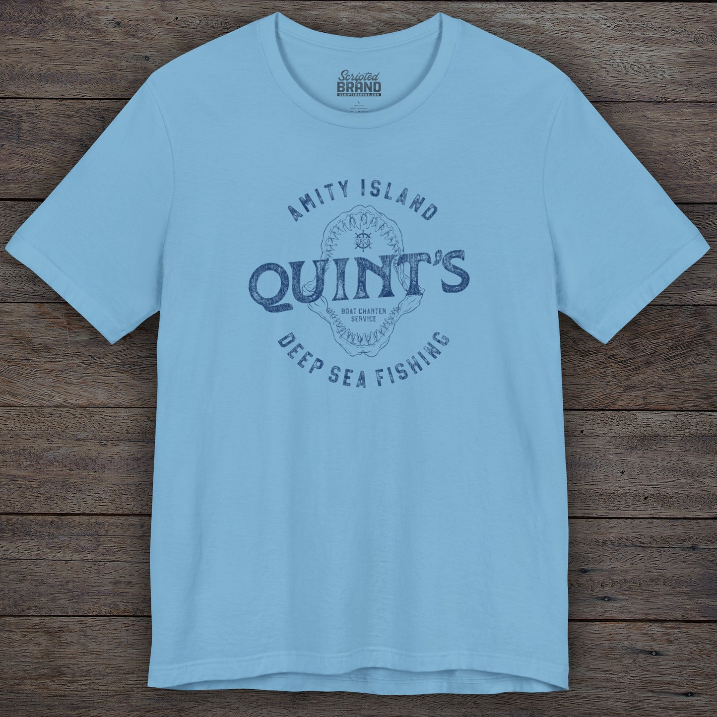 Ocean blue colored Soft short-sleeve t-shirt featuring the Quint's Deep Sea Fishing Boat Charters logo graphic inspired by the movie Jaws in a vintage distressed ink-stamped worn-in style.