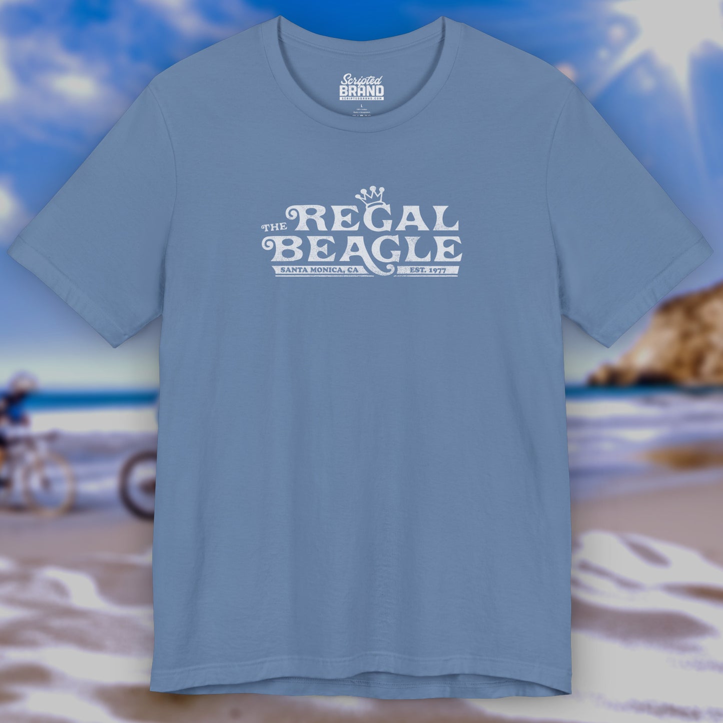 Front view of a Lavender Blue colored soft Bella+Canvas 3001 short-sleeve t-shirt featuring the Regal Beagle logo from the TV Show Threes Company in a vintage distressed style.