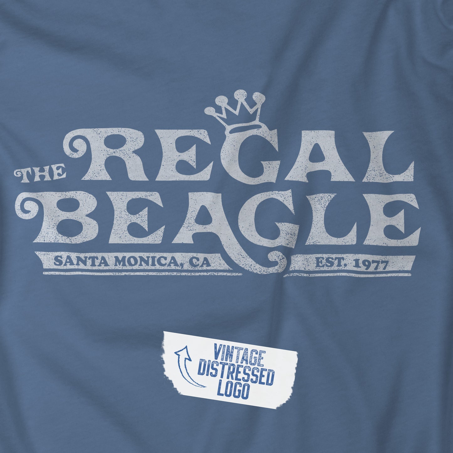 Closeup view of a Lavender Blue colored soft Bella+Canvas 3001 short-sleeve t-shirt featuring the Regal Beagle logo from the TV Show Threes Company in a vintage distressed style.