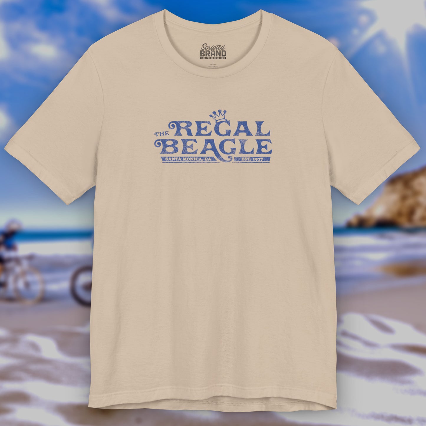 Front view of a tan colored soft Bella+Canvas 3001 short-sleeve t-shirt featuring the Regal Beagle logo from the TV Show Threes Company in a vintage distressed style.