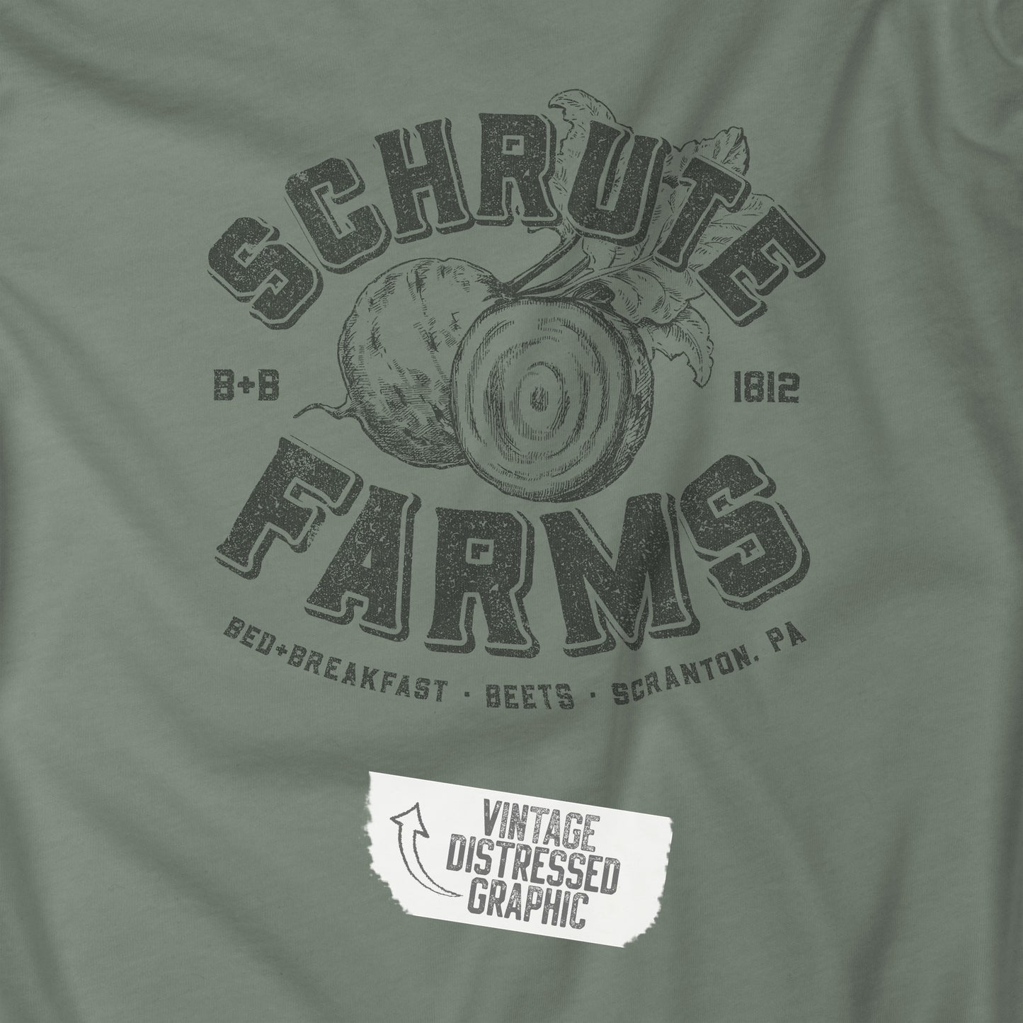 Closeup of Sage green t-shirt featuring a Schrute Farms logo from the TV show The Office designed by ScriptedBrand in a vintage distressed style.
