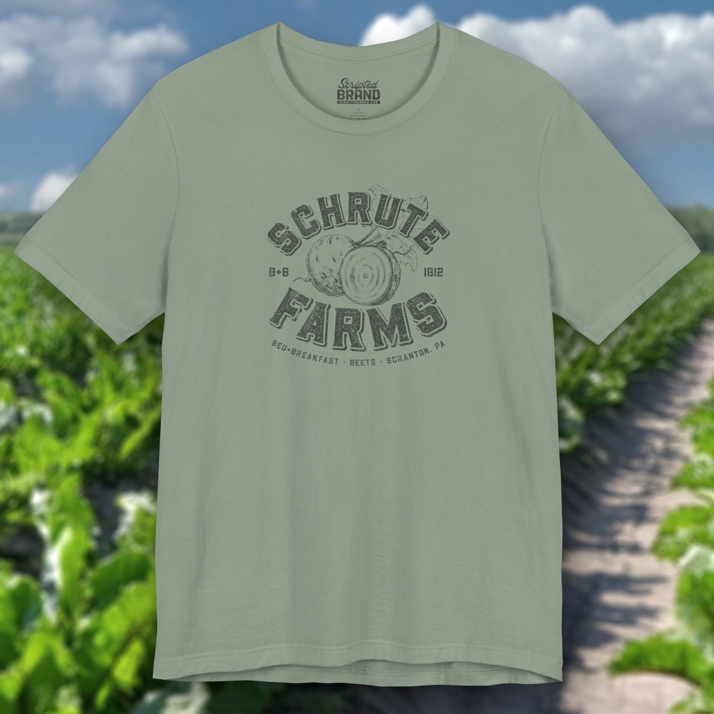 Sage green t-shirt featuring a Schrute Farms logo from the TV show The Office designed by ScriptedBrand in a vintage distressed style.