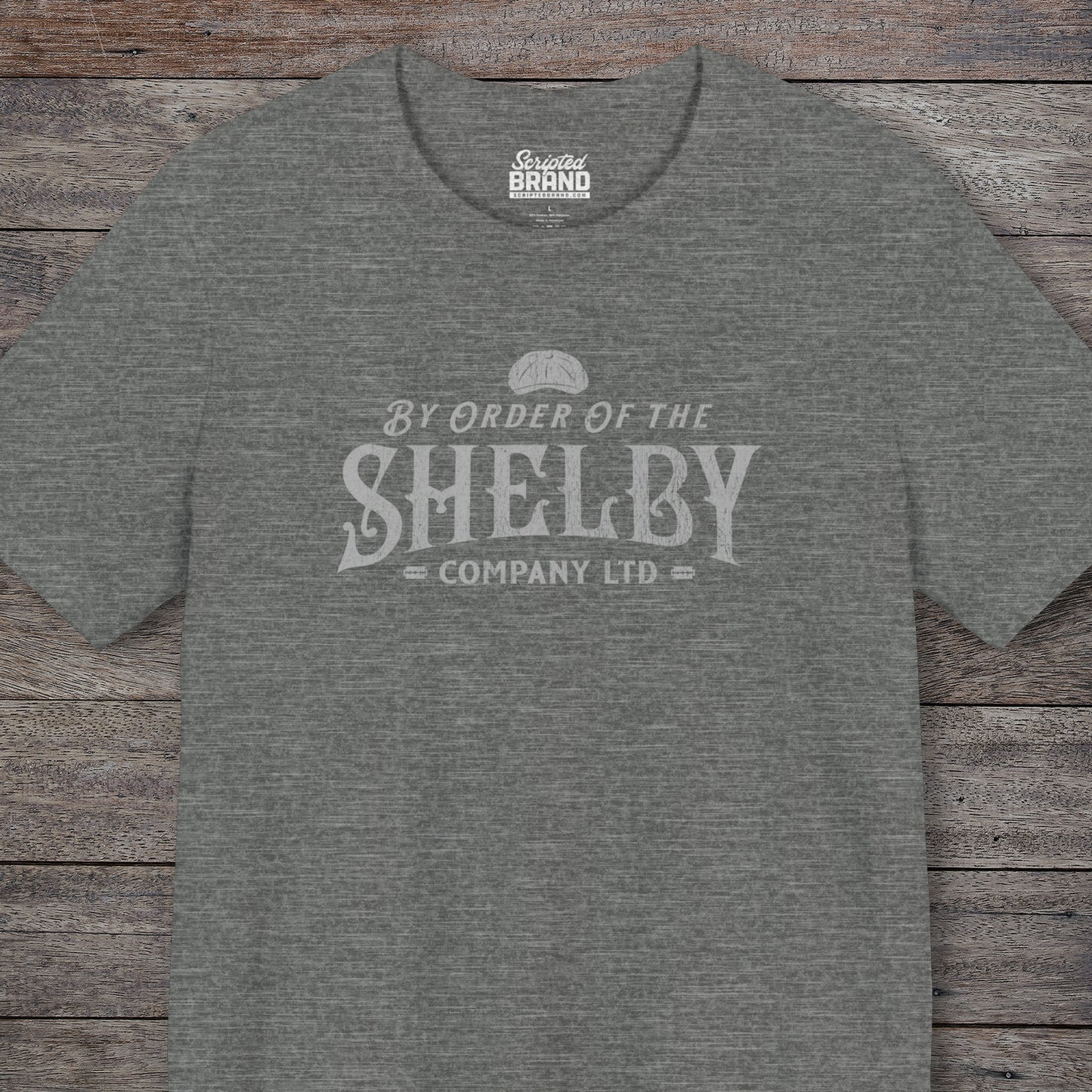 Front view of a deep heather grey colored soft short-sleeve Bella+Canvas 3001 t-shirt featuring a unique Shelby Company Limited logo graphic from the show Peaky Blinders and movie The Immortal Man, in a vintage distressed style, includes a flat cap and razor blades, designed and sold by ScriptedBrand.