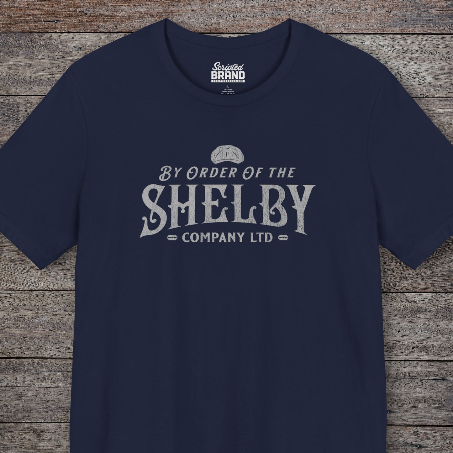 Front view of a Navy blue colored soft short-sleeve Bella+Canvas 3001 t-shirt featuring a unique Shelby Company Limited logo graphic from the show Peaky Blinders and movie The Immortal Man, in a vintage distressed style, includes a flat cap and razor blades, designed and sold by ScriptedBrand.