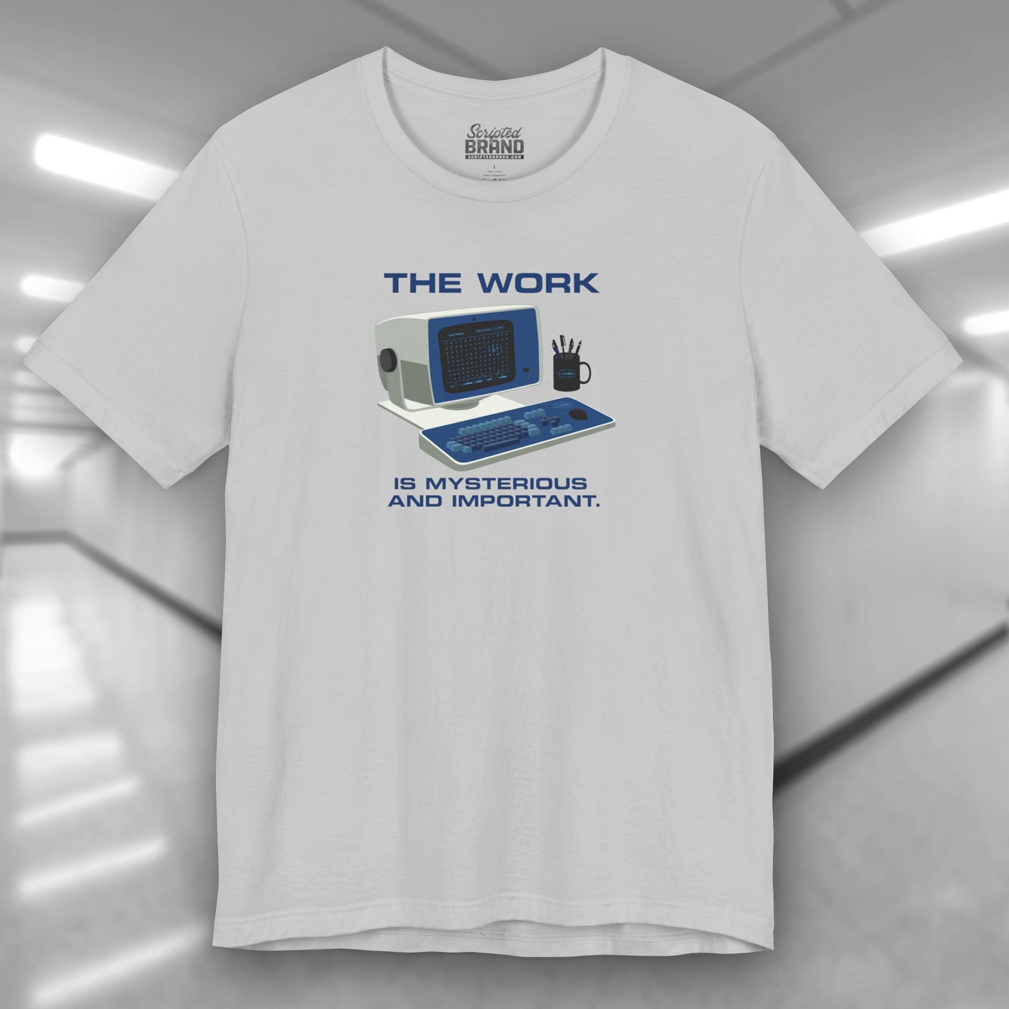 Front view of a solid athletic grey Soft Bella+Canvas shirtsleeve t-shirt featuring the retro computer workstation from the Apple TV show Severance, and includes the text The Work is Mysterious and Important. Graphic is designed and illustrated by ScriptedBrand.