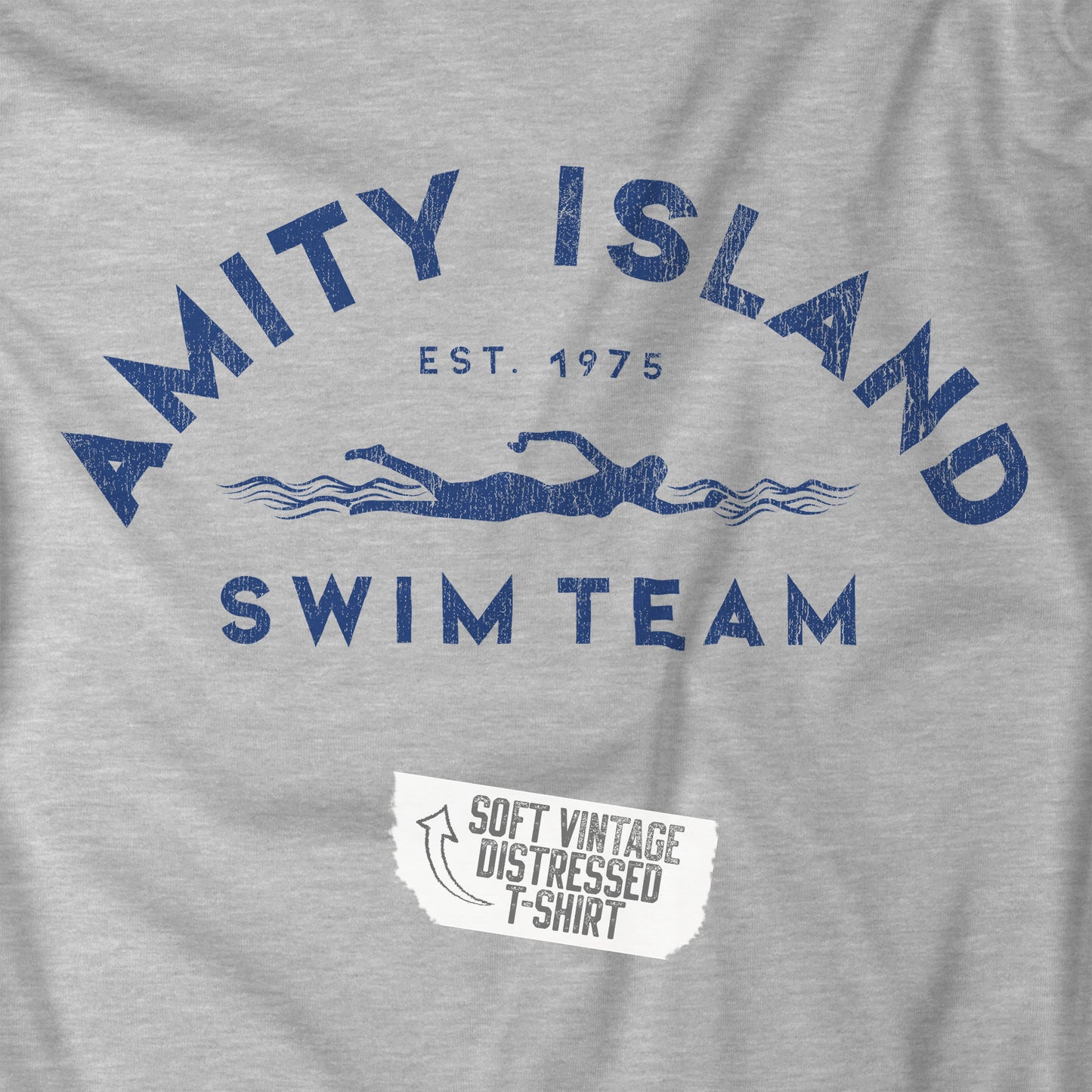 Closeup view of an athletic heather grey colored Soft unisex Youth Sizes Bella+Canvas 3001Y short-sleeve t-shirt featuring an Amity Island Swim Team logo graphic, designed by ScriptedBrand, and inspired by the movie Jaws in a vintage distressed style.