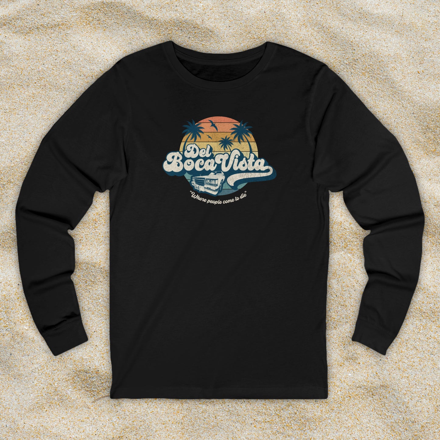 Front view of a black Soft Bella+Canvas 3501 long-sleeve t-shirt featuring a Del Boca Vista logo graphic (uniquely designed by ScriptedBrand), including the phrase Where People Come To Die, inspired by the TV show Seinfeld, in a vintage distressed style.
