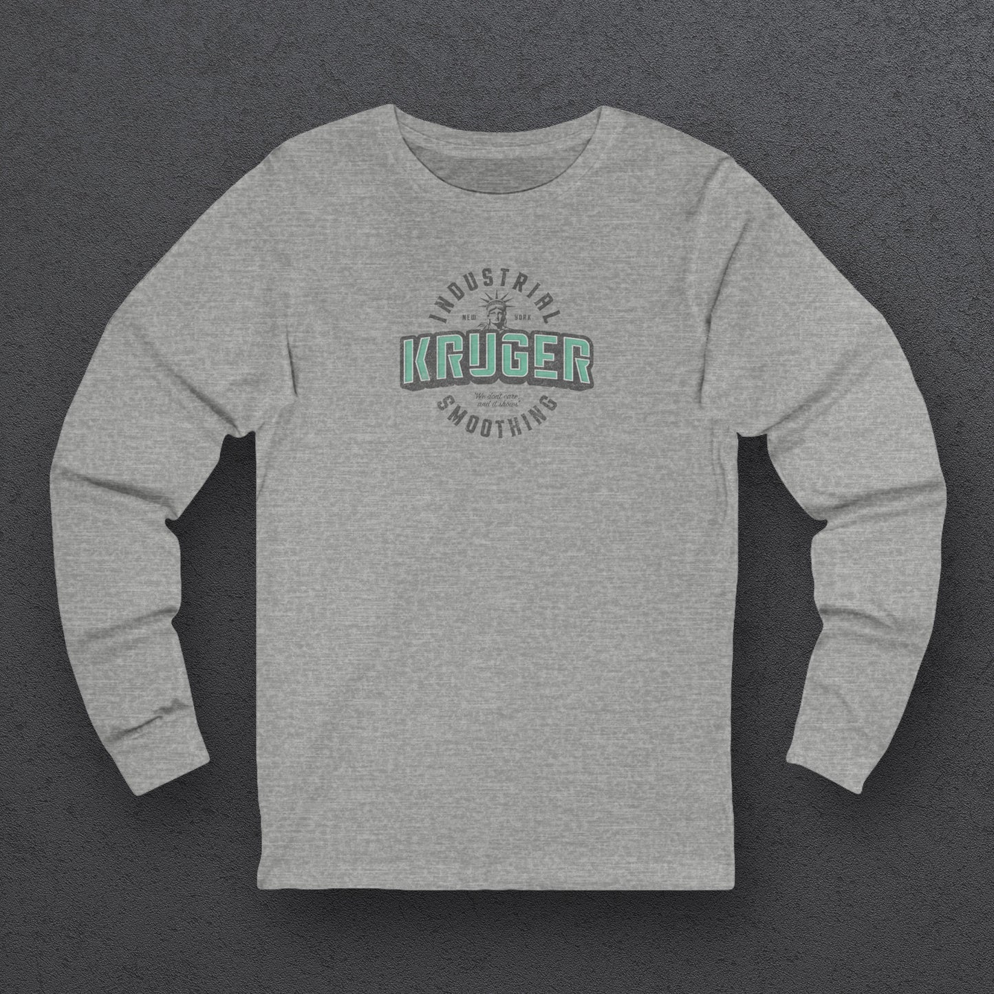 Front view of a grey athletic heather colored soft unisex Bella+Canvas 3501 long-sleeve t-shirt featuring a Kruger Industrial Smoothing logo graphic, designed by ScriptedBrand in a vintage distressed style, and inspired by the TV show Seinfeld. Includes the Statue of Liberty and the the slogan "We don't care and it shows".