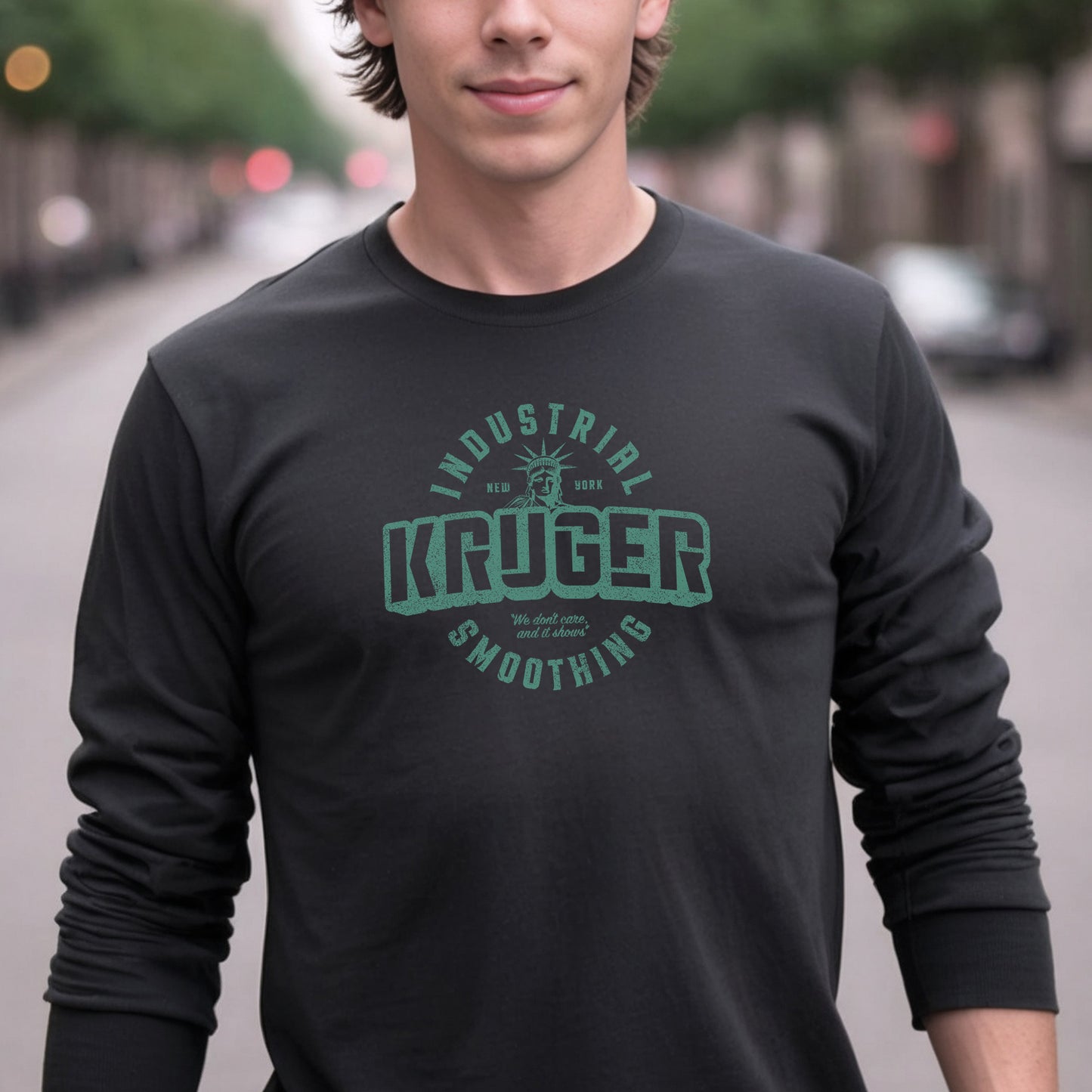 Male model wearing a black colored soft unisex Bella+Canvas 3501 long-sleeve t-shirt featuring a Kruger Industrial Smoothing logo graphic, designed by ScriptedBrand in a vintage distressed style, and inspired by the TV show Seinfeld. Includes the Statue of Liberty and the the slogan "We don't care and it shows".