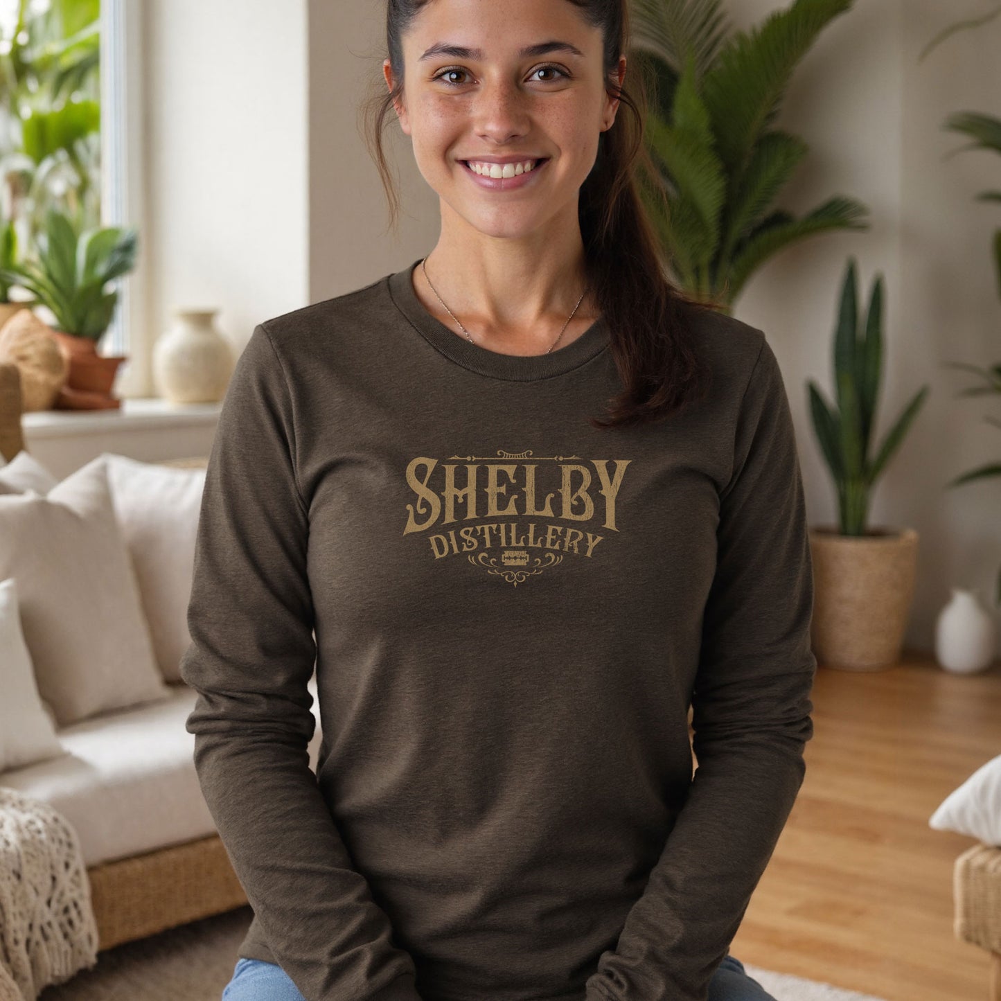 Female model wearing a heather brown Soft Unisex Bella+Canvas 3501 long-sleeve t-shirt featuring a Shelby Company Limited Distillery Logo Graphic inspired by the TV show Peaky Blinders in a vintage distressed style, sold by ScriptedBrand.