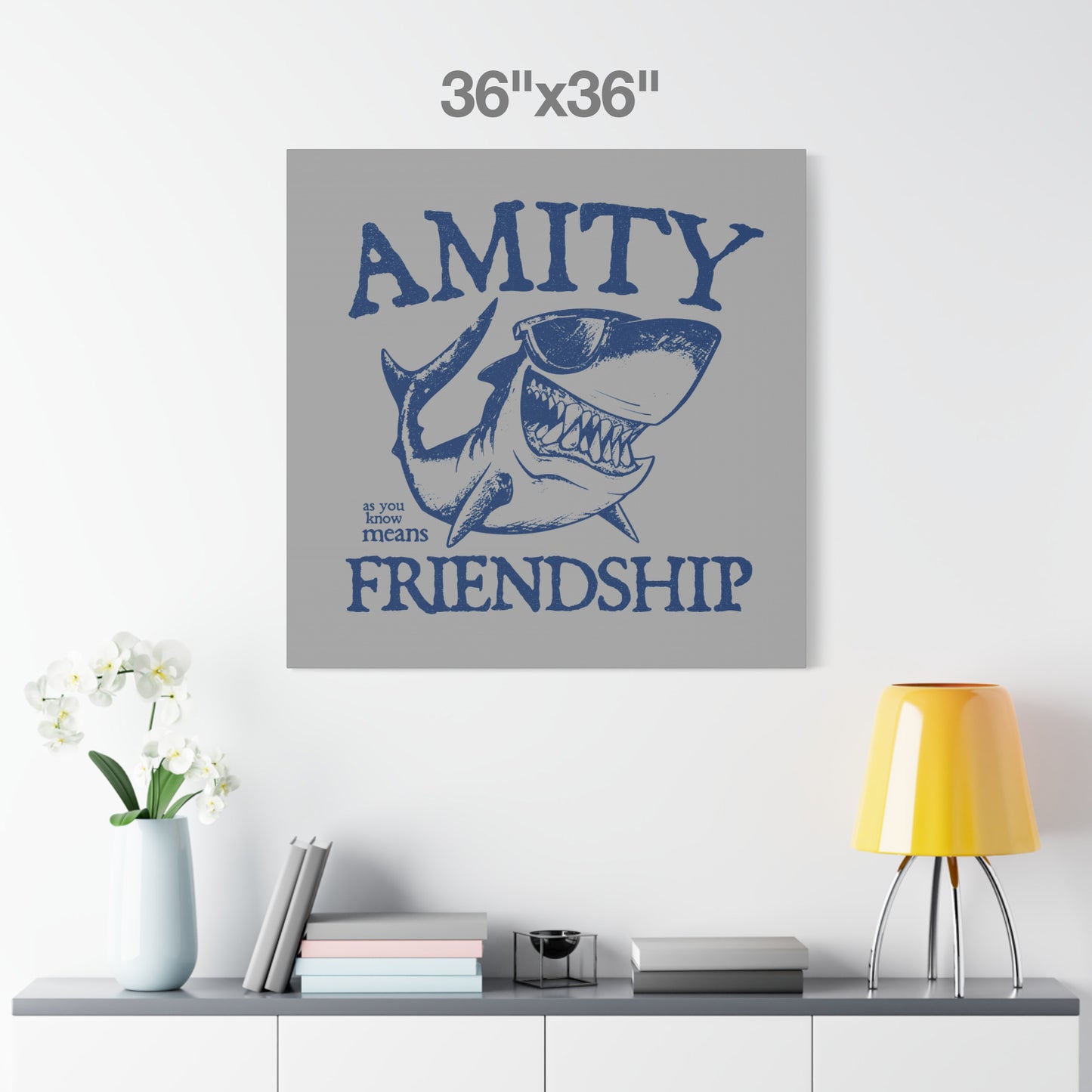 36 x 36 Funny Amity Island shark wall art canvas print inspired by Jaws with “Amity Means Friendship” and shark in sunglasses, on a white wall.