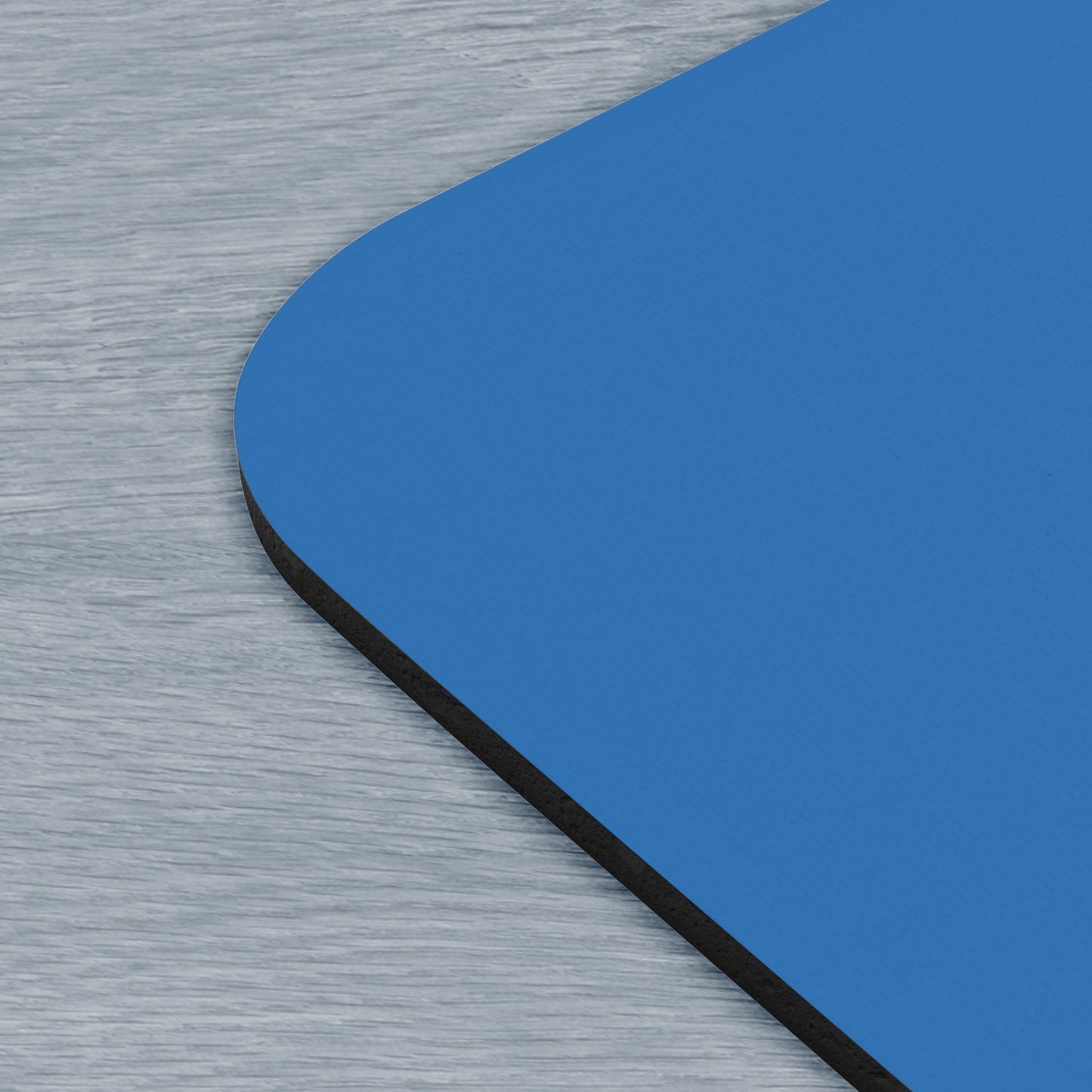 Corner view of a 9x8 modern blue Mouse pad with the Lumon Industries logo from the TV show Severance, next to a MacBook.