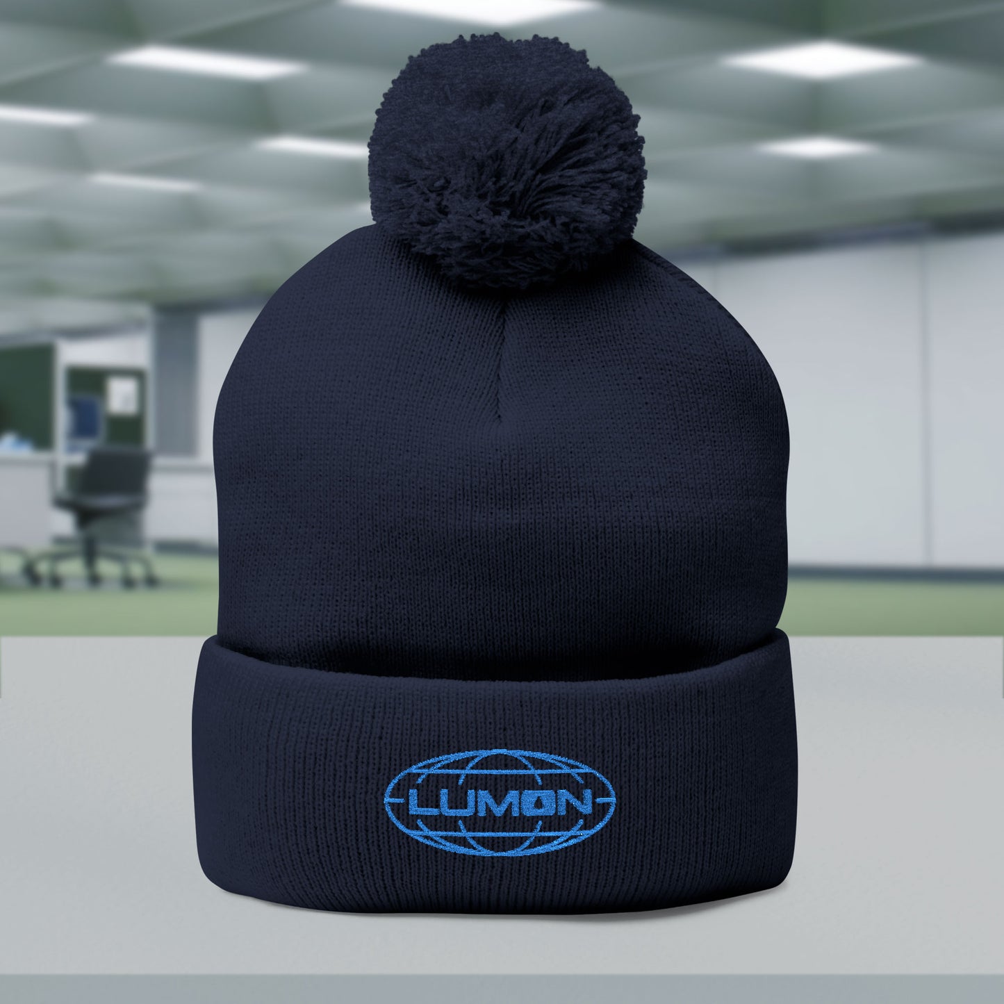 Navy Blue colored Pom-Pom Winter Knit Hat featuring the embroidered blue logo of Lumon Industries from the Apple TV Show Severance on the front.