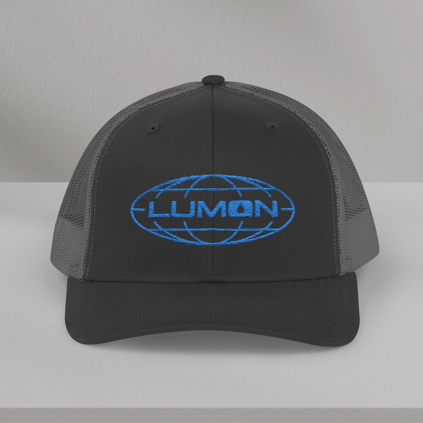 Front view of a black/charcoal gray Embroidered Snapback Trucker Cap featuring the blue logo of Lumon Industries from the Apple TV Show Severance.