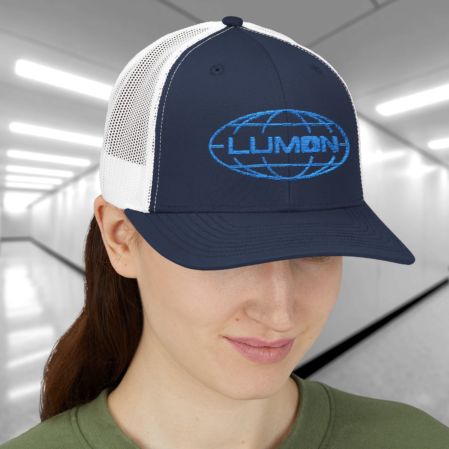 Female model wearing a navy/white Embroidered Snapback Trucker Cap featuring the blue logo of Lumon Industries from the Apple TV Show Severance.