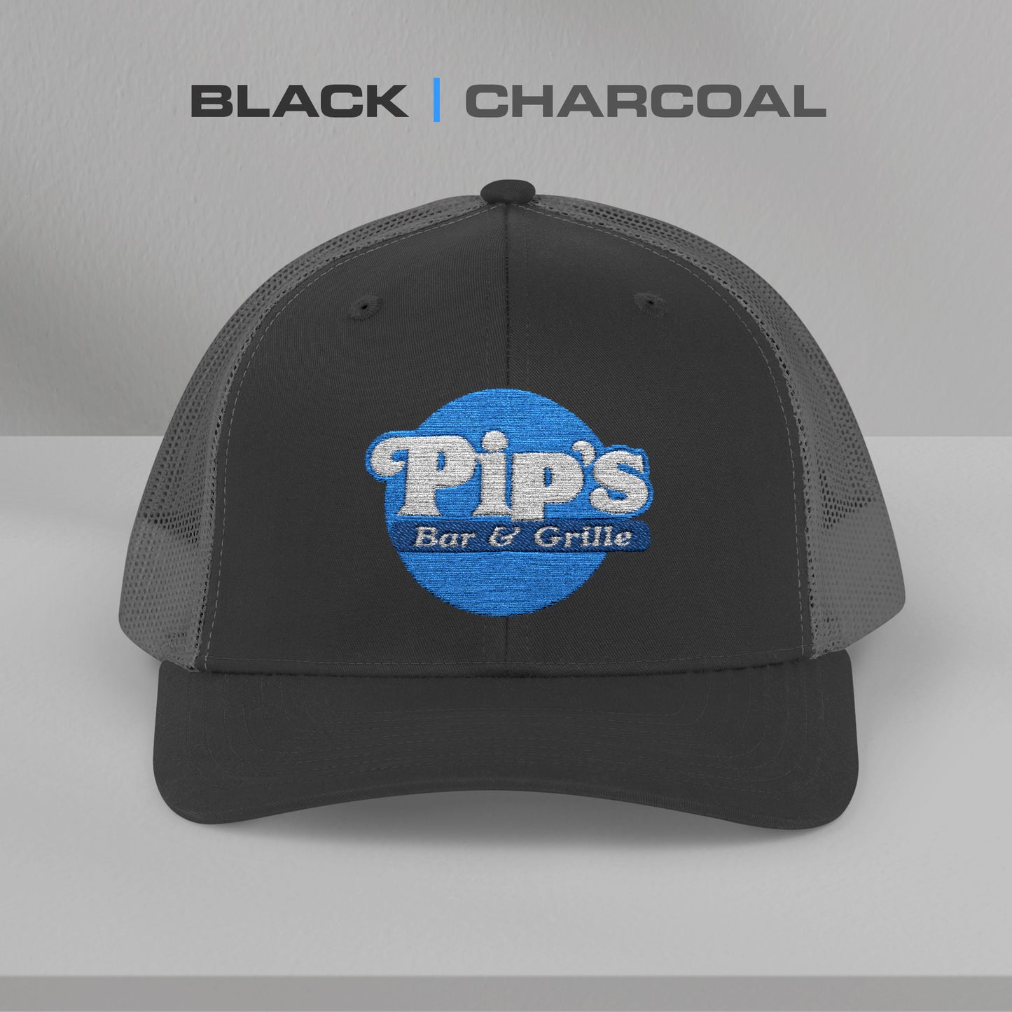Front view of a black/charcoal Snapback Trucker Cap featuring an embroidered Pip's Bar and Grill logo from the Apple TV show Severance.