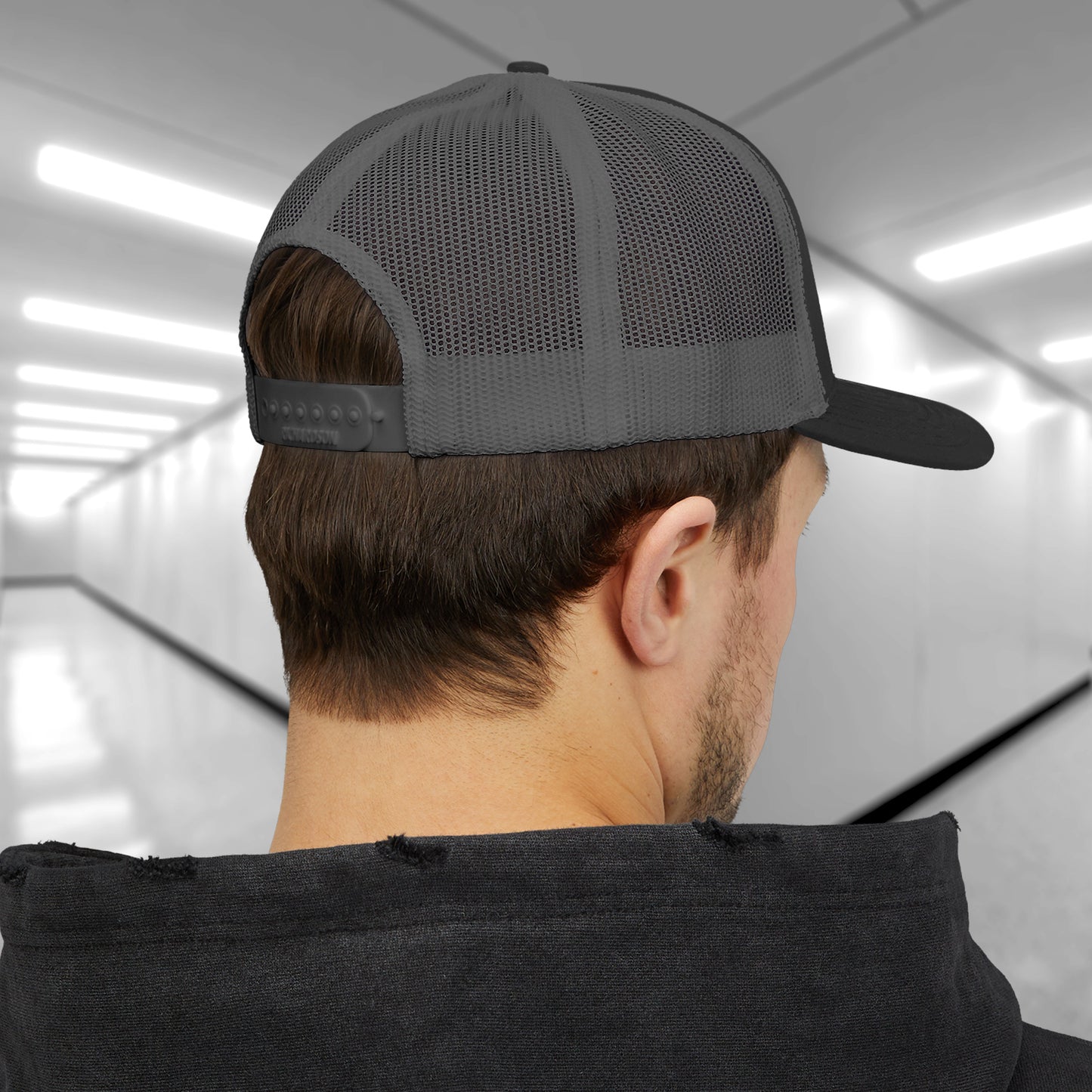 Rear view of a male model wearing a black Snapback Trucker Cap featuring an embroidered Pip's Bar and Grill logo from the Apple TV show Severance.