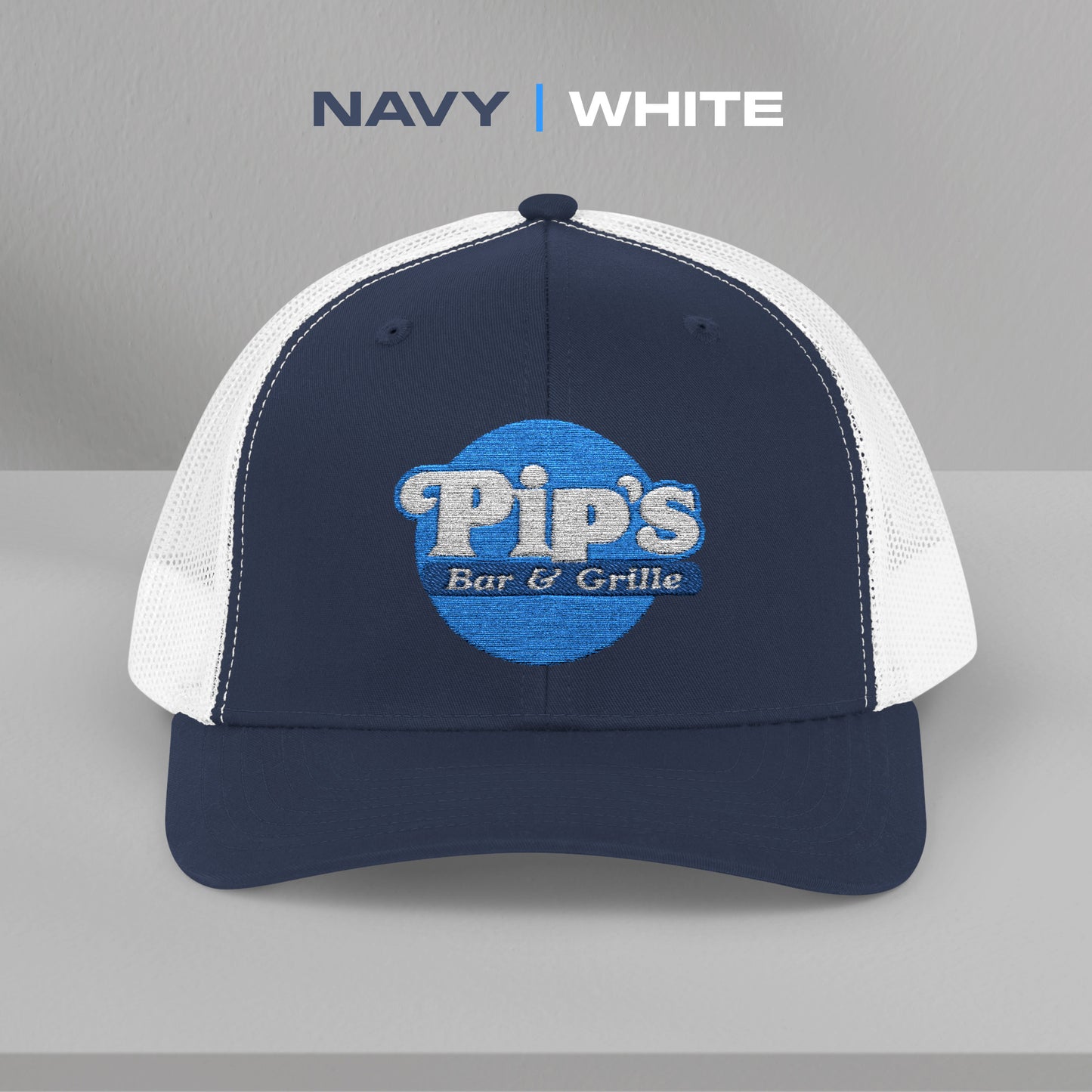 Front view of a navy/white Snapback Trucker Cap featuring an embroidered Pip's Bar and Grill logo from the Apple TV show Severance.