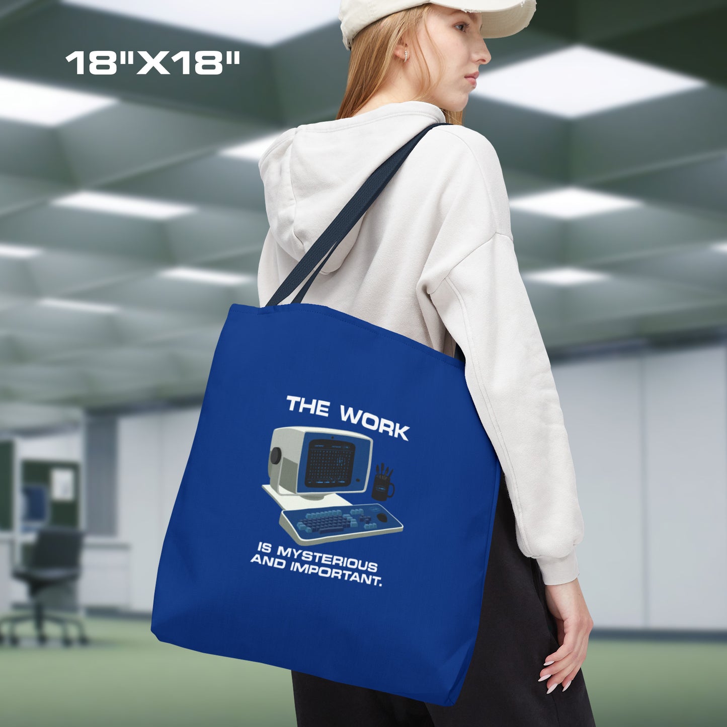 Female model holding a Large Blue Tote Bag (18" x 18") featuring the retro computer workstation from the Apple TV show Severance, and includes the text The Work is Mysterious and Important. Graphic is designed and illustrated by ScriptedBrand.