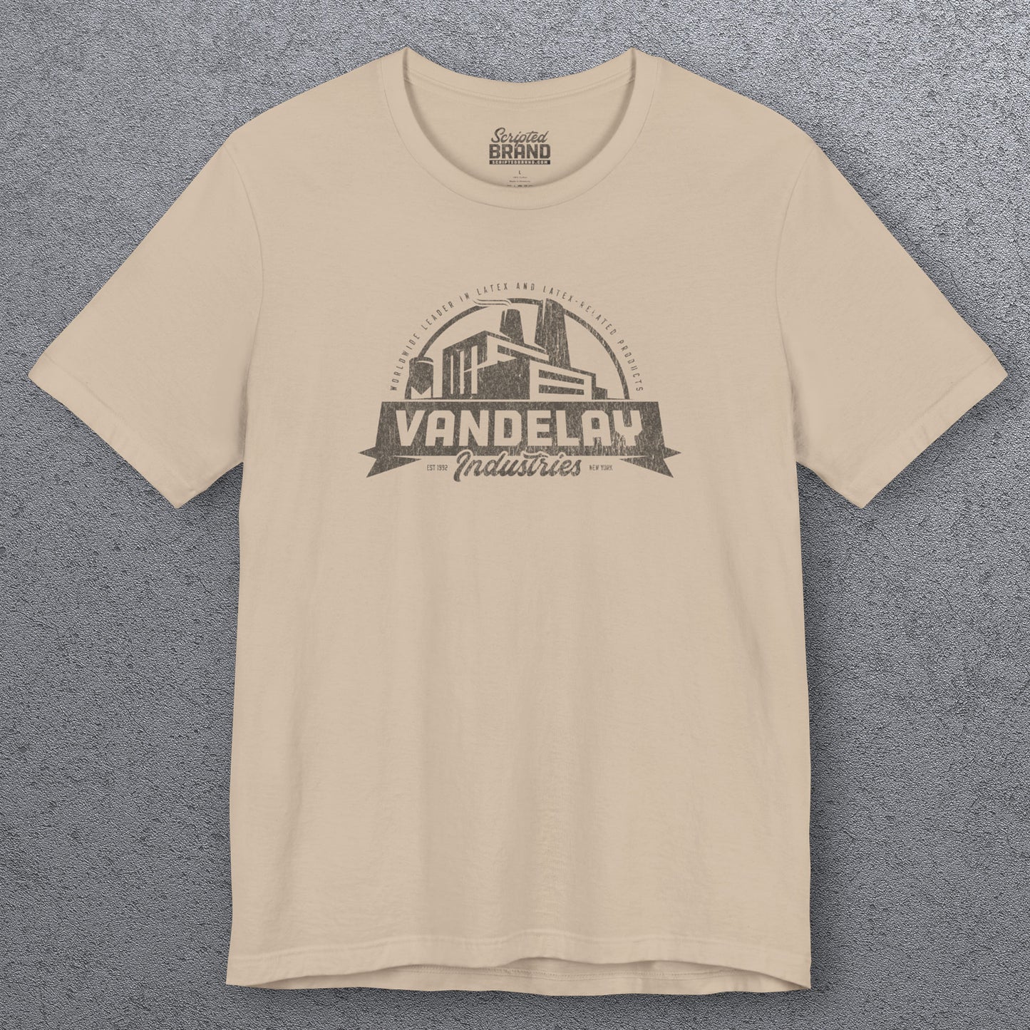 Front view of a tan Soft Bella+Canvas 3001 short-sleeve t-shirt tee featuring a Vandelay Industries logo graphic, uniquely designed by ScriptedBrand in a vintage distressed style. The fictional company is part of the George Costanza storyline in the TV show Seinfeld.