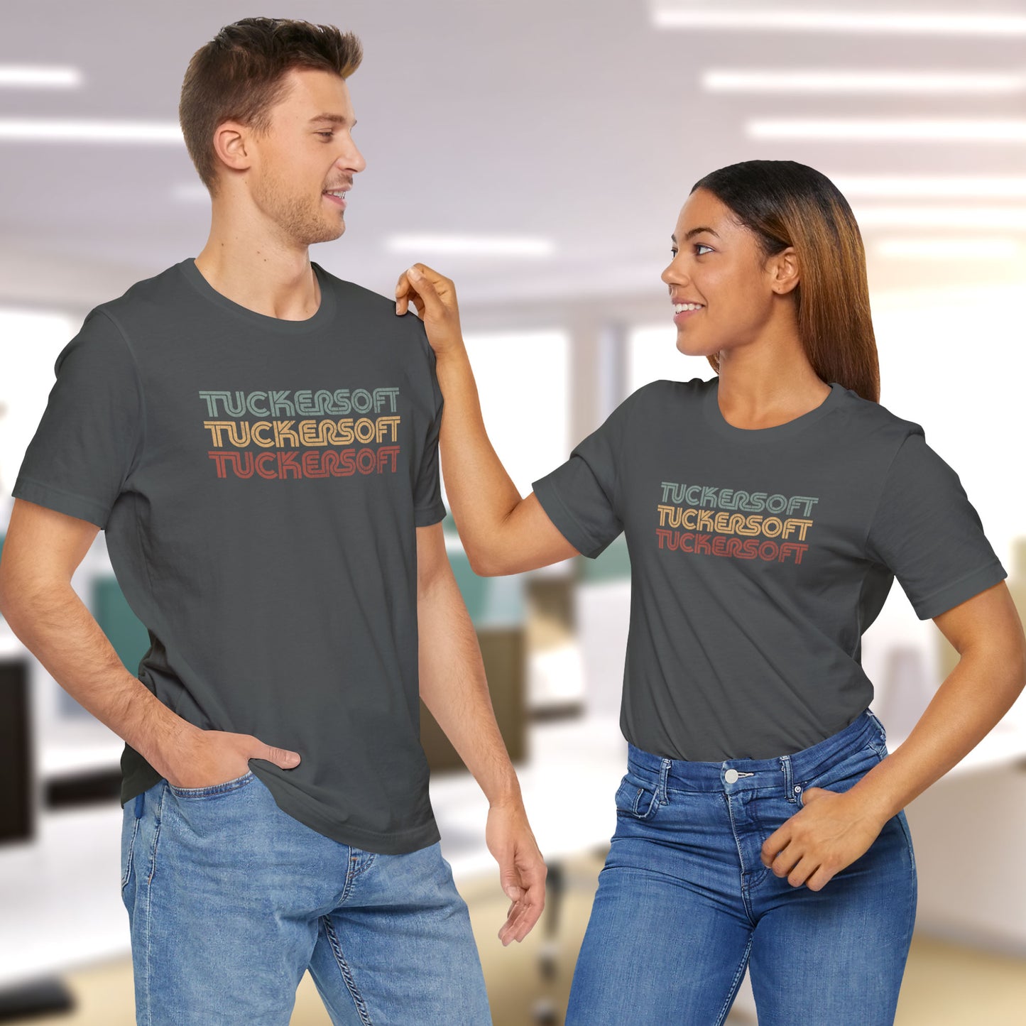 2 models wearing asphalt grey soft Bella+Canvas 3001 short-sleeve t-shirt tee featuring a logo graphic of the 1980s fictional video game company Tuckersoft inspired by the TV show Black Mirror and the episode Bandersnatch in a vintage distressed style, sold by ScriptedBrand.
