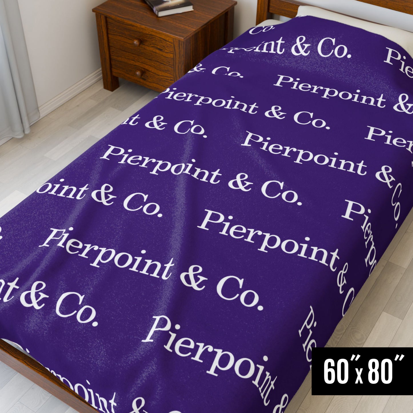 60" x 80" Velveteen Plush Blanket with a step and repeat pattern of Pierpoint & Co. logo from the HBO TV show Industry, on a small bed.