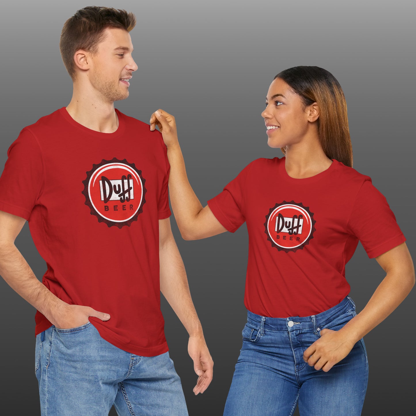 Two people wearing red t-shirts featuring the Duff Beer bottle cap logo from the TV Show The Simpsons in vintage distressed style.