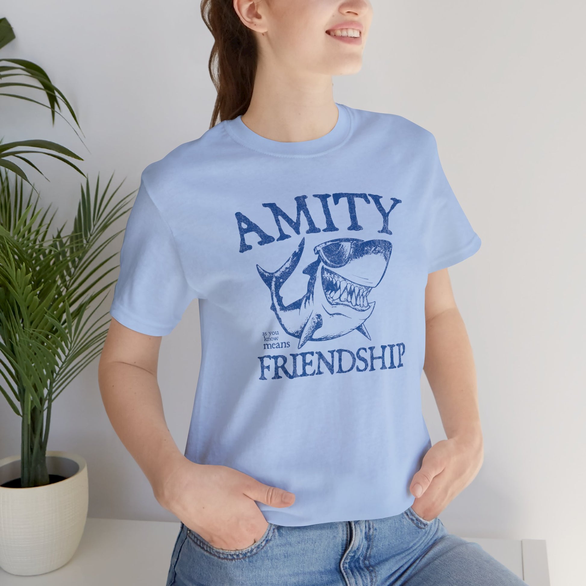 Female wearing blue Bella+Canvas t-shirt with a vintage-style Amity Island “Friendship” shark graphic inspired by the movie Jaws