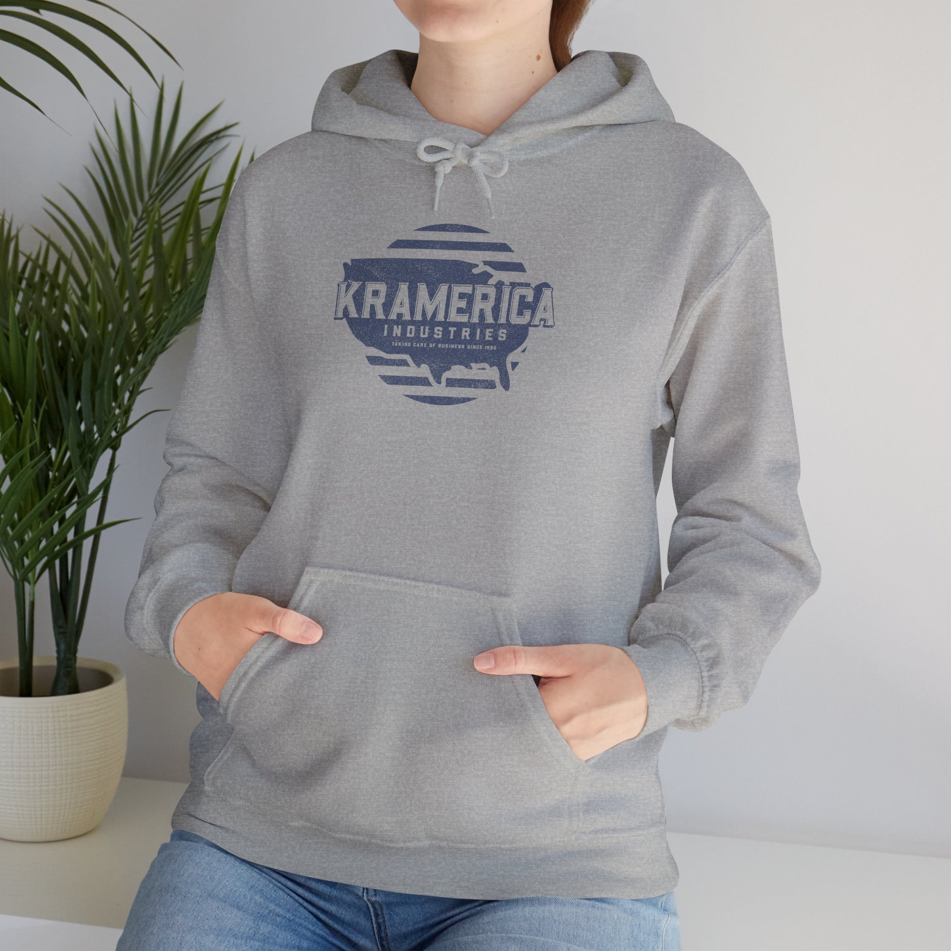 Woman wearing Heather Gray Hoodie Sweatshirt featuring a Kramerica logo inspired by Seinfeld, designed by ScriptedBrand in a vintage distressed style.