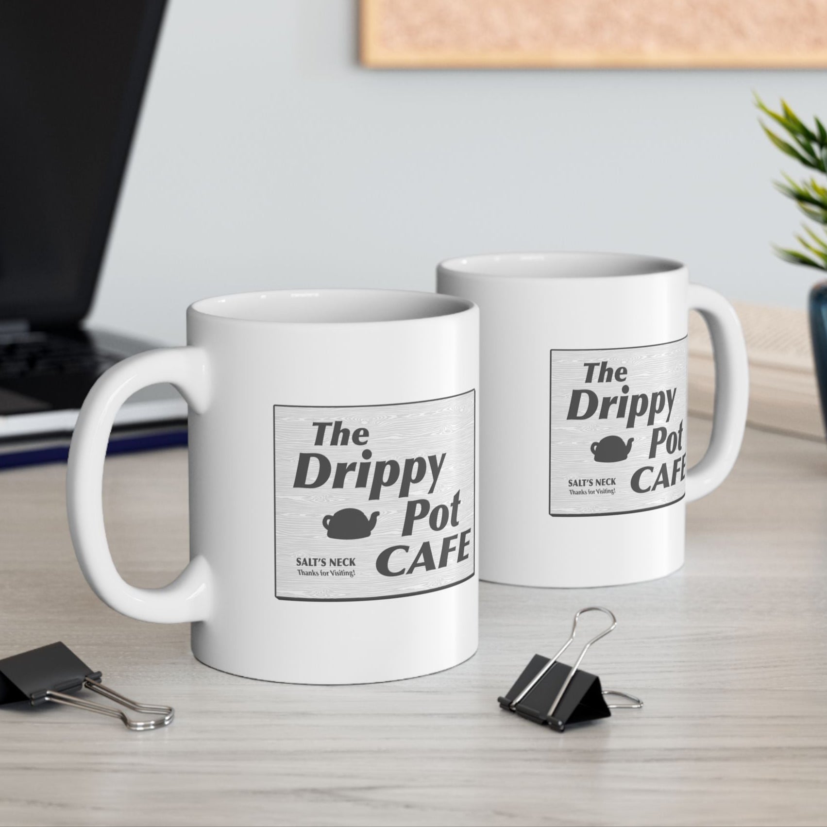 11 oz White Ceramic Mugs on desk with the Drippy Pot Cafe logo graphic from the TV show Severance